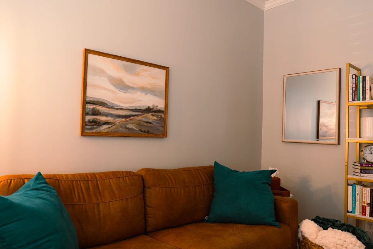 Therapy room with sofa, framed landscape artwork, and accent pillows.