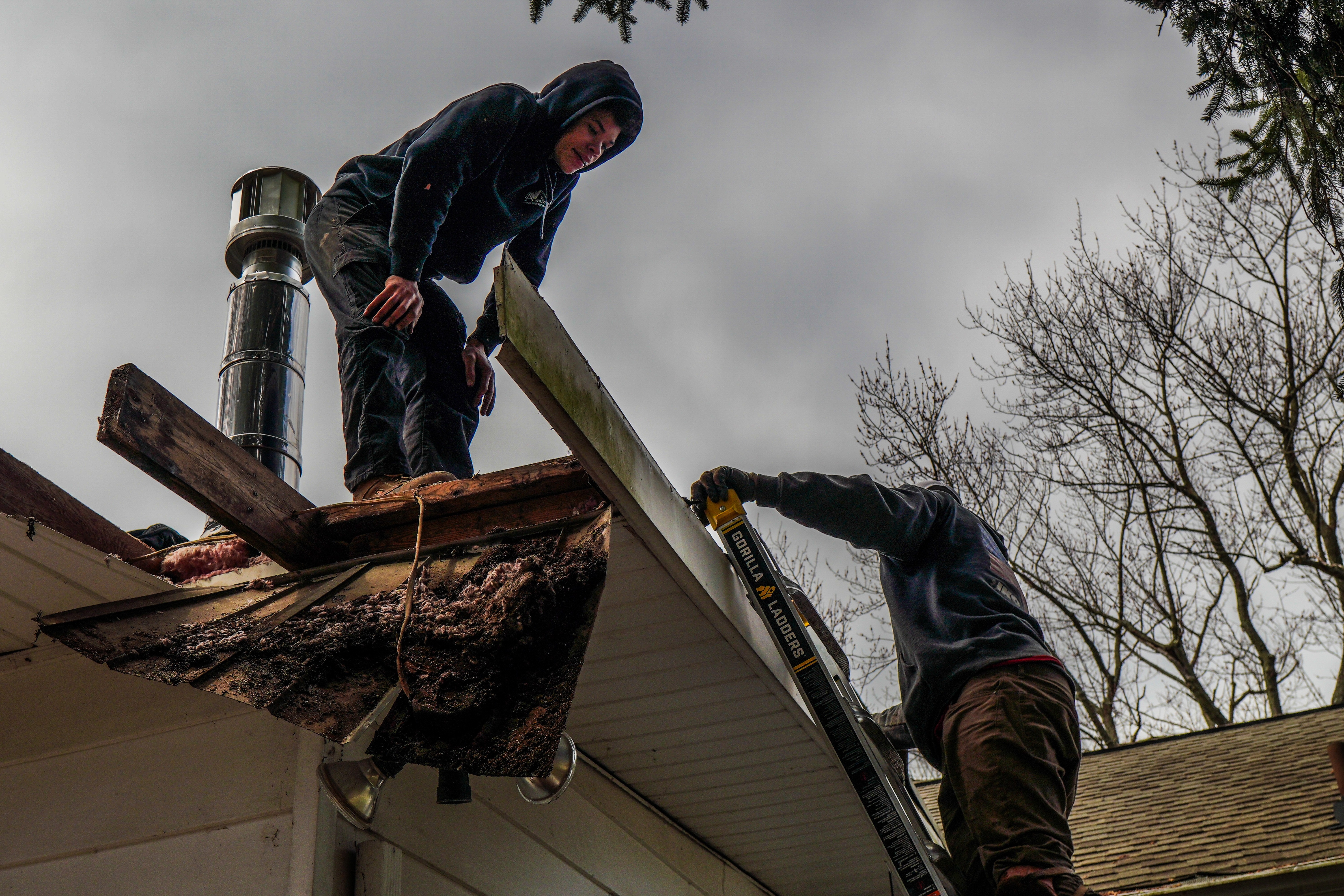 Roofing crew removing old roofing near a chimney