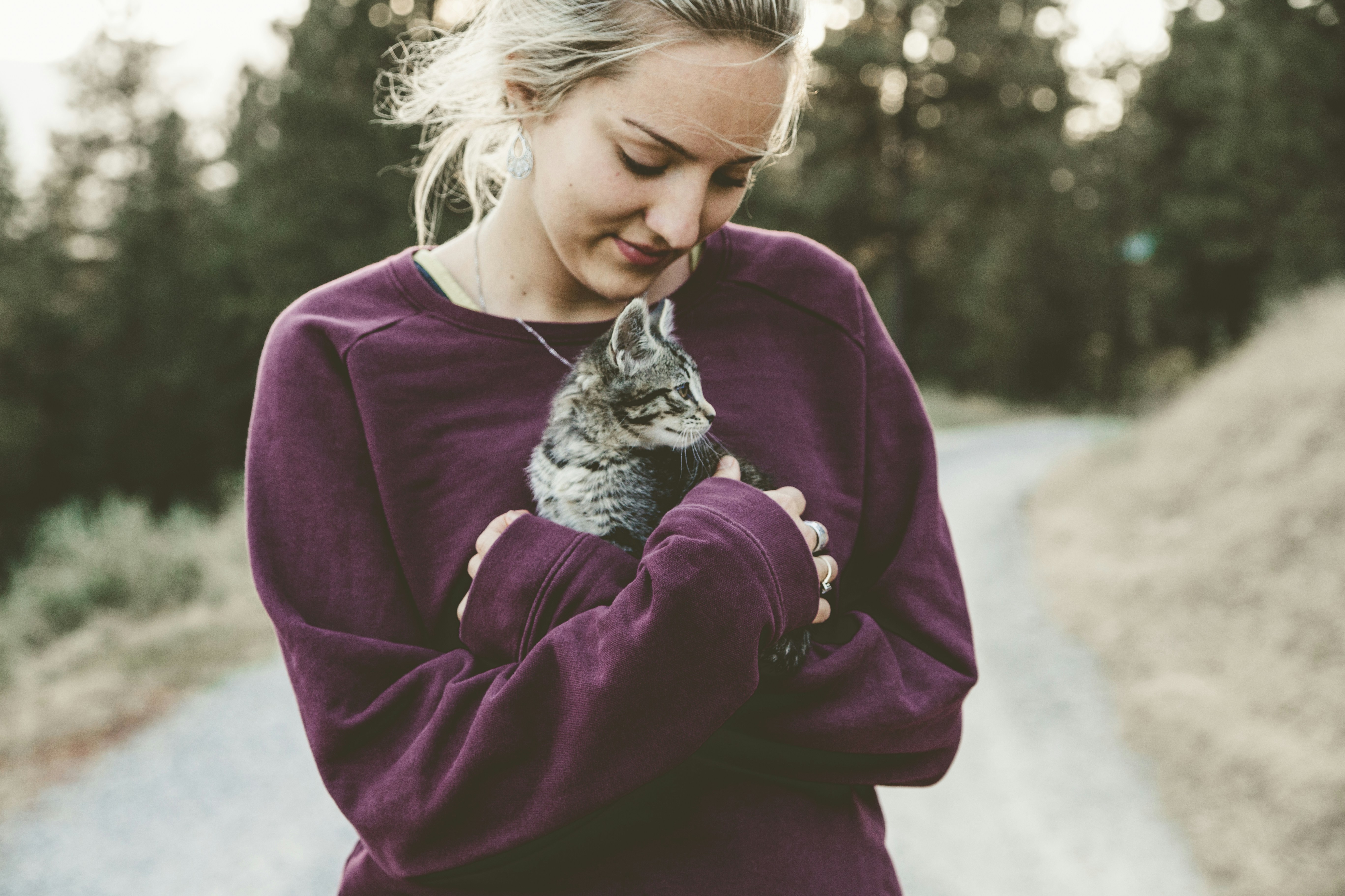 Picture of a young woman holding a kitten in her arms outside