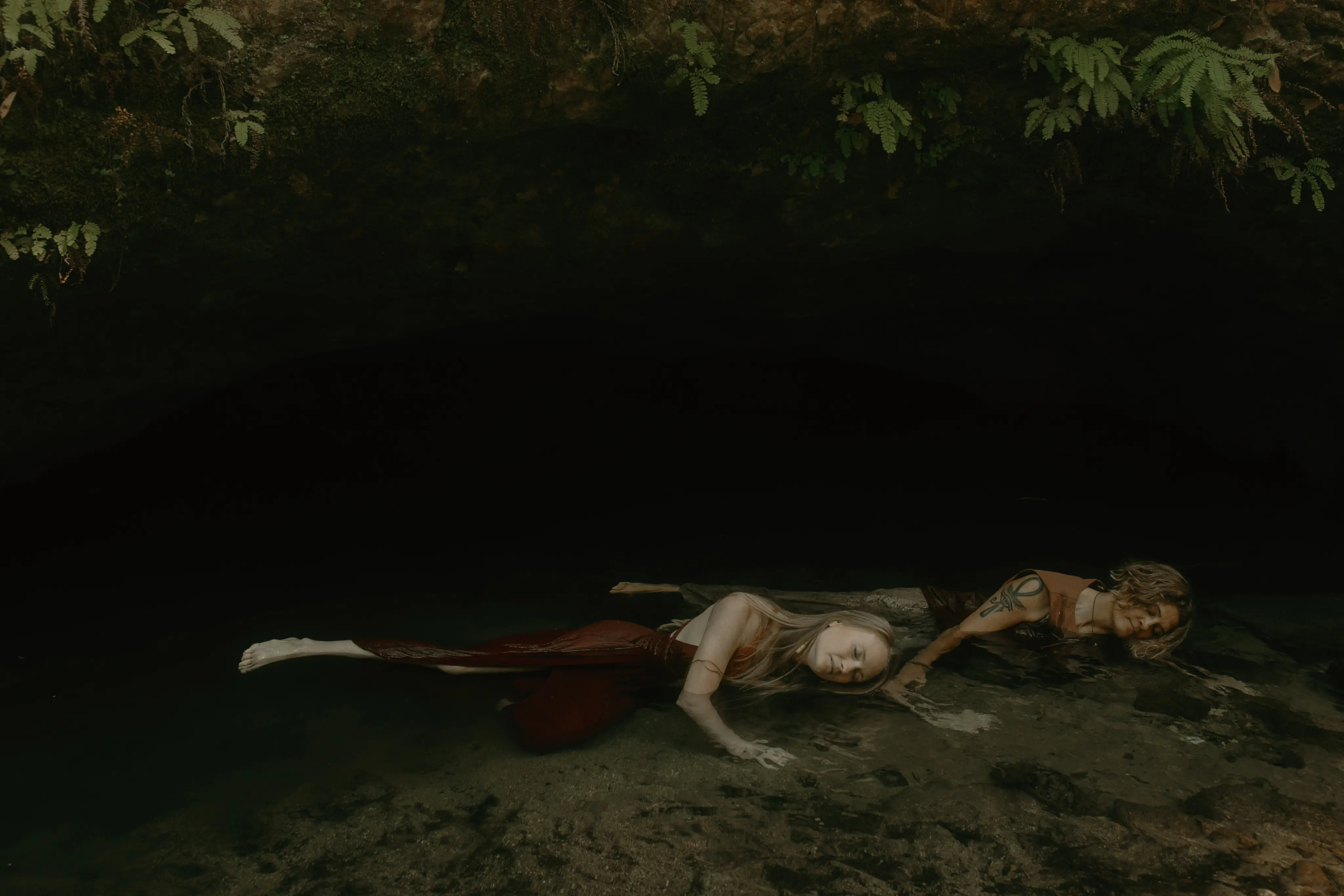 Person lying in surrender in dark water during plant medicine ceremony
