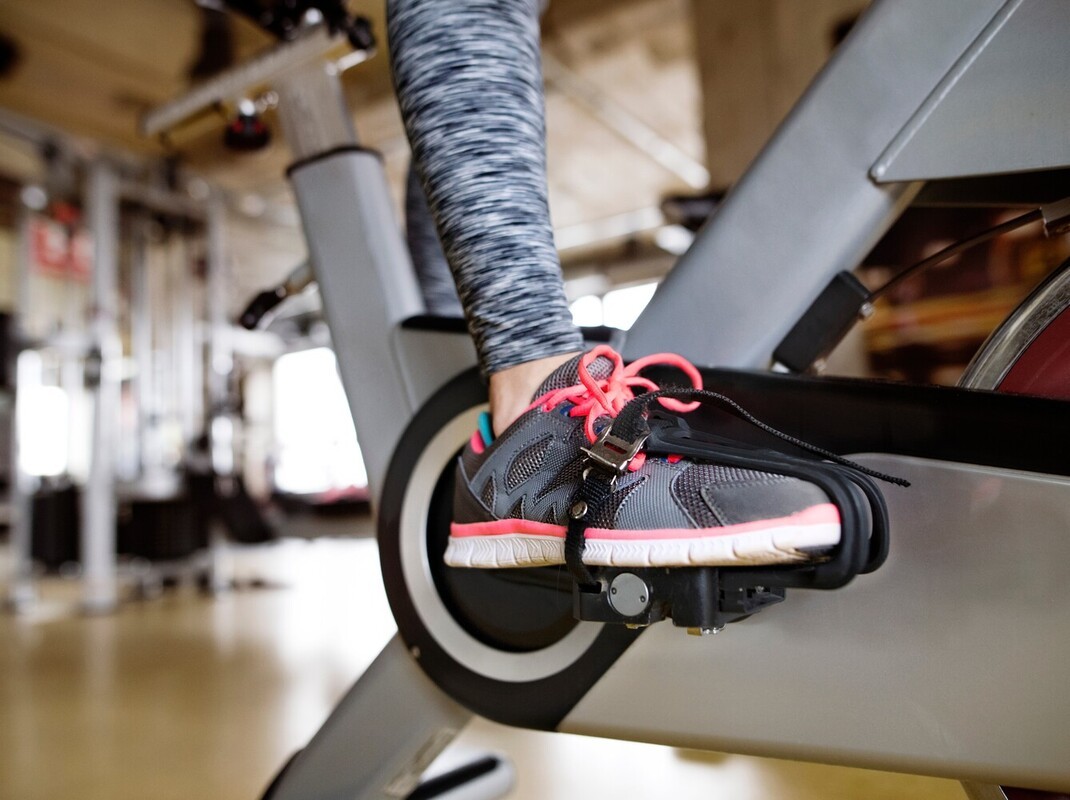 close-up of a woman bike riding to lose weight on a stationary bike in the gym