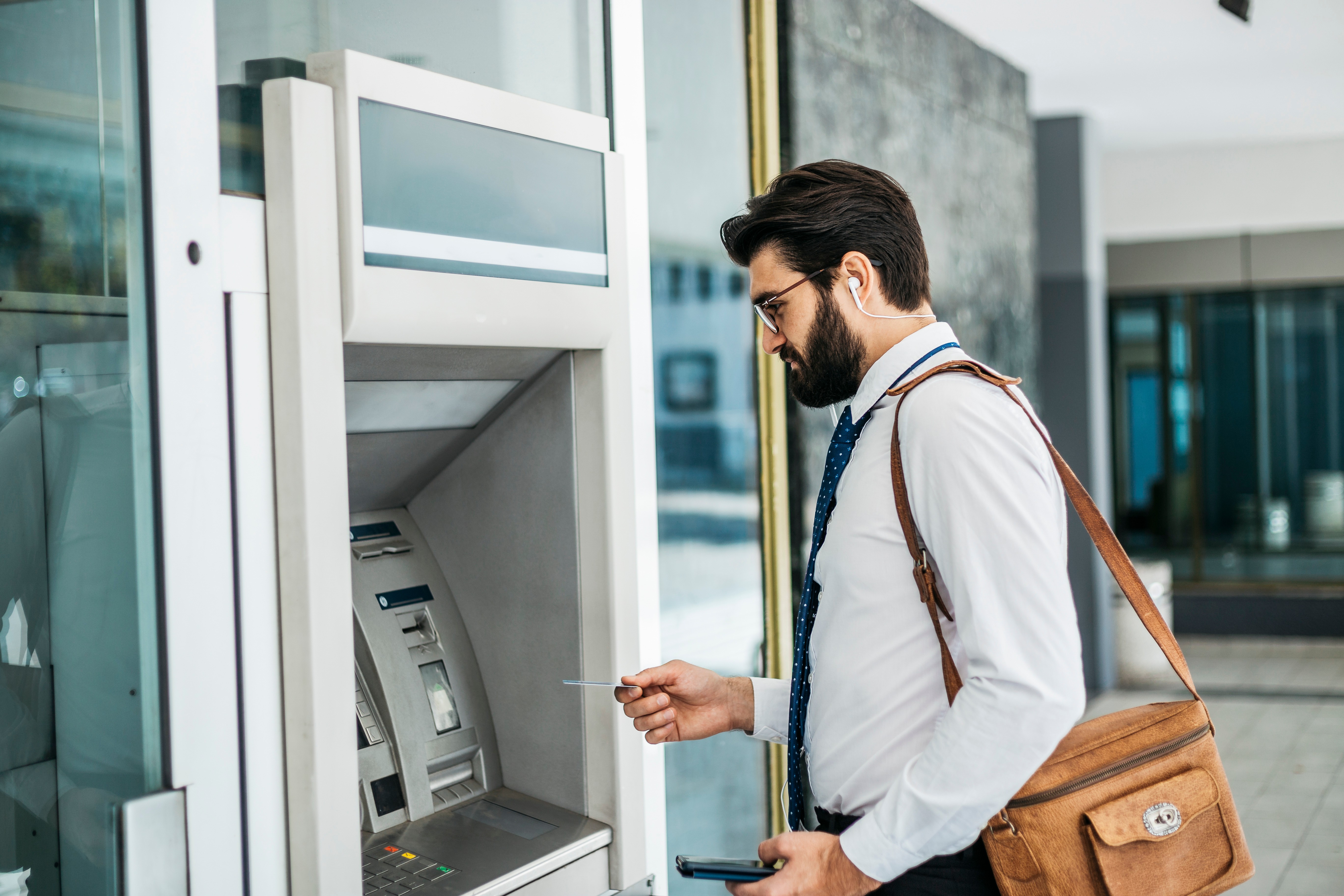 a man about to withdraw money from an ATM. the ability to get money from an ATM 24/7 is essential for our society