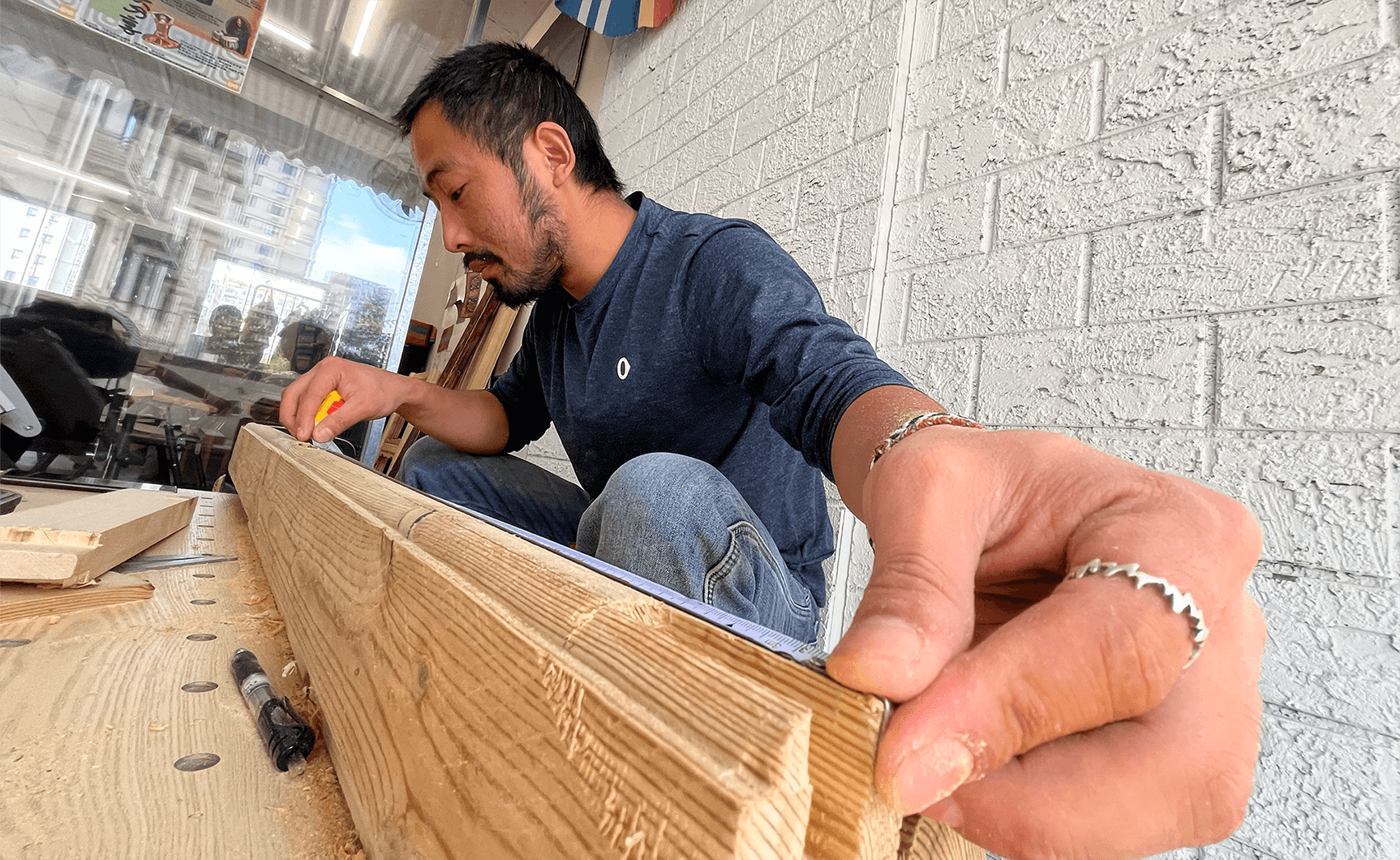 Close-up photo of a collaborator measuring wood for the Shaardaa furniture piece during the design process.