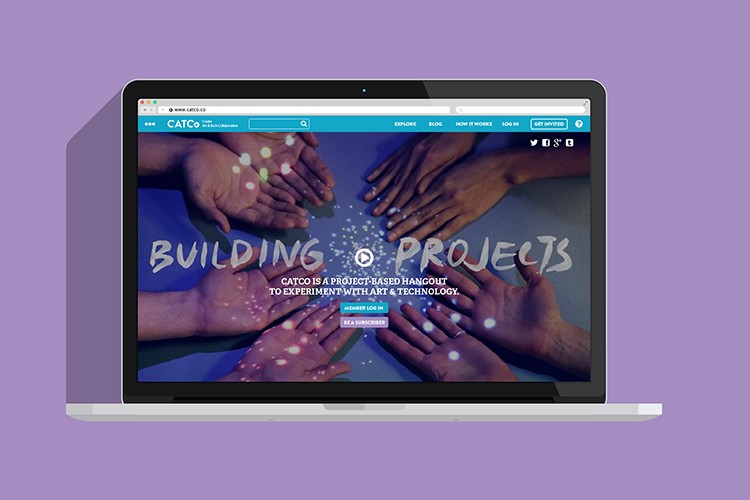 A laptop screen displays a website titled "BUILDING PROJECTS" with a background image of hands reaching toward a blue surface. The text below the title reads, "CATCO IS A PROJECT BASED HANGOUT TO EXPERIMENT WITH ART & TECHNOLOGY." A navigation bar includes tabs like "EXPLORE," "BLOG," "HOW IT WORKS," and "LOG IN." A "GET MYRTES" button is visible in the top right corner. The laptop is positioned on a light purple background.