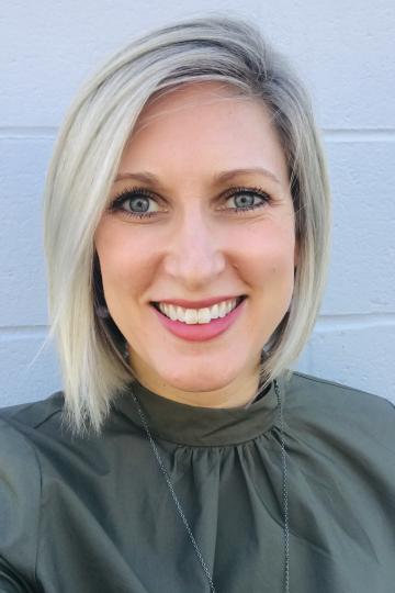 Smiling woman with short blonde hair and a green shirt looking directly at the camera.
