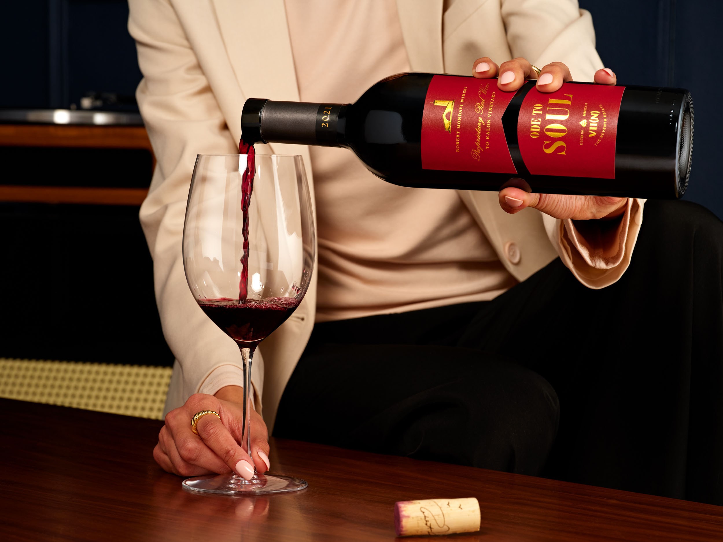 Ode to Soul red wine being poured into a stemmed glass beside the bottle cork