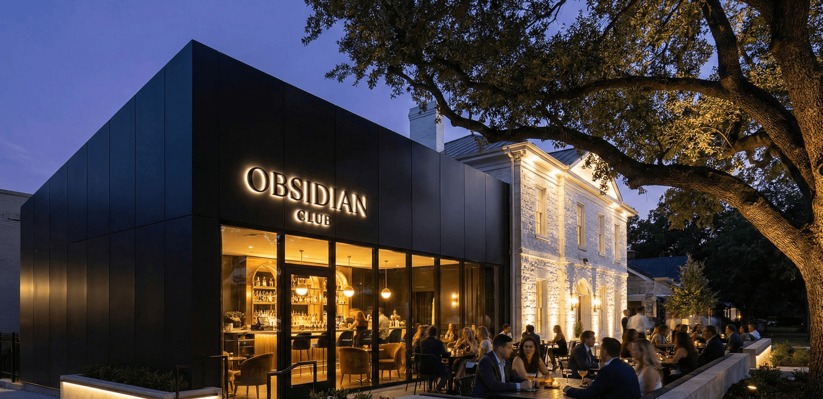 A modern restaurant with a sleek black exterior, warmly lit, set against a twilight sky and surrounded by trees.