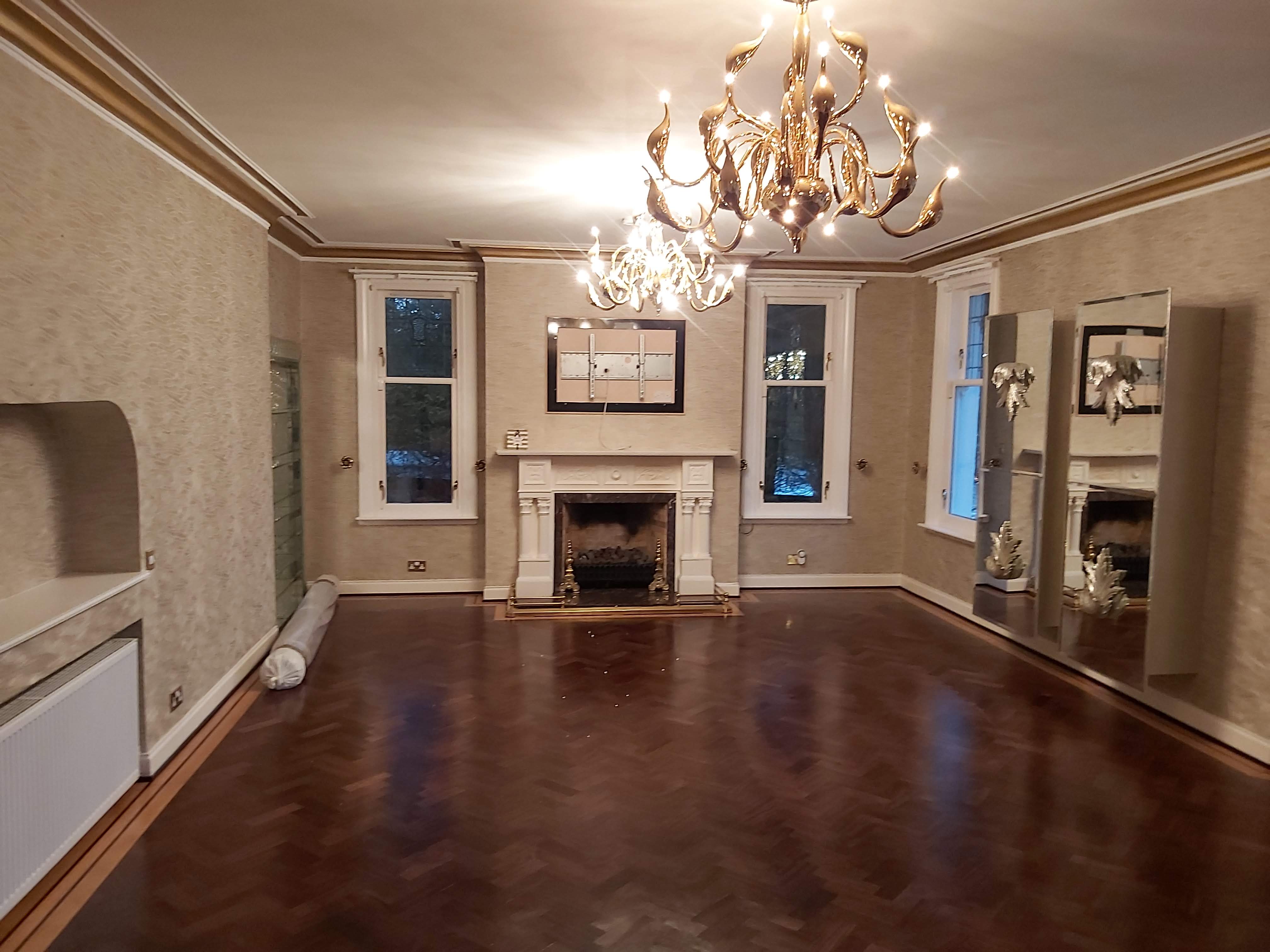 Inside a livingroom with wooden floors and patterned wallpaper