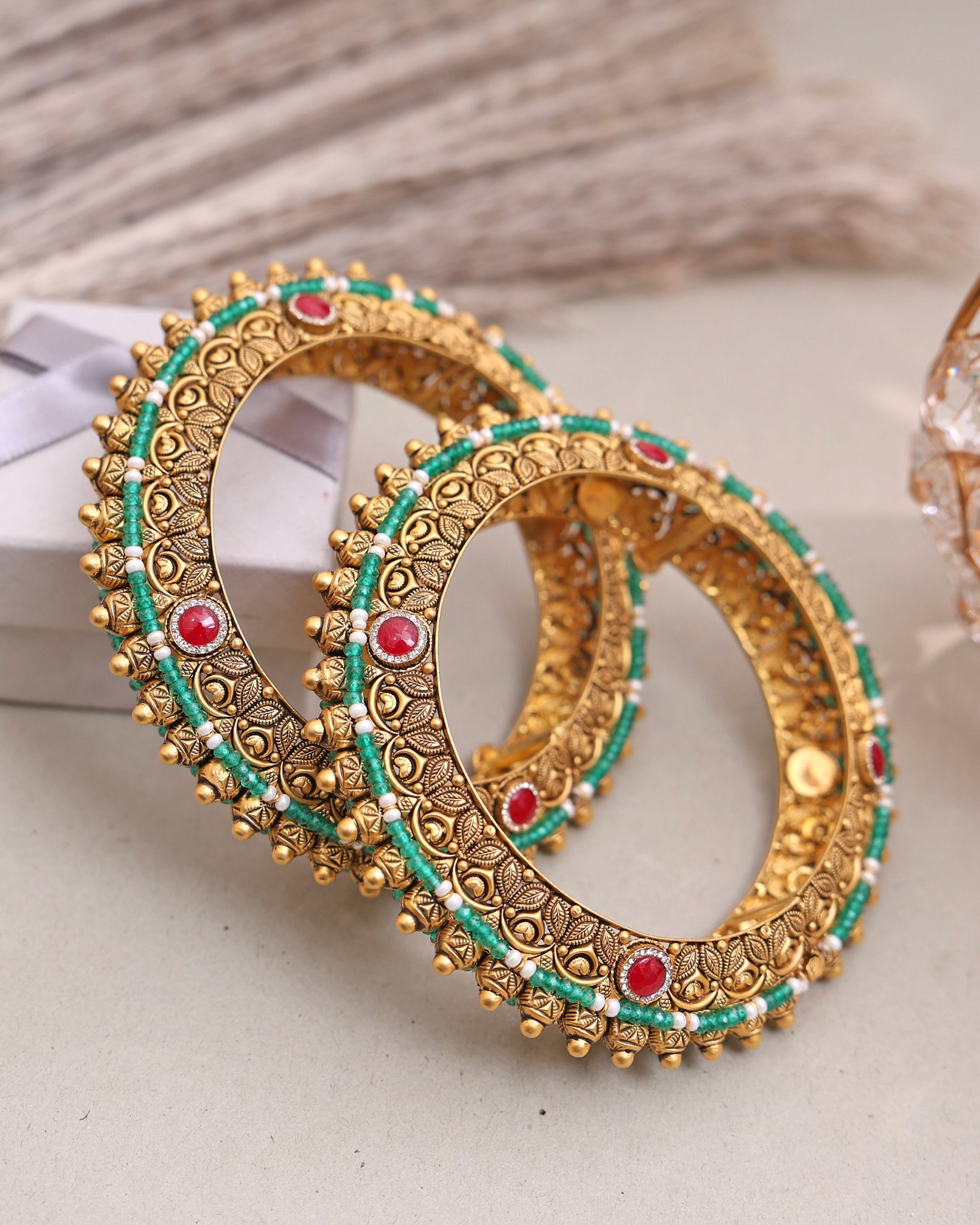 Pair of antique gold bangles with red and green stone embellishments by Jora Jewellers
