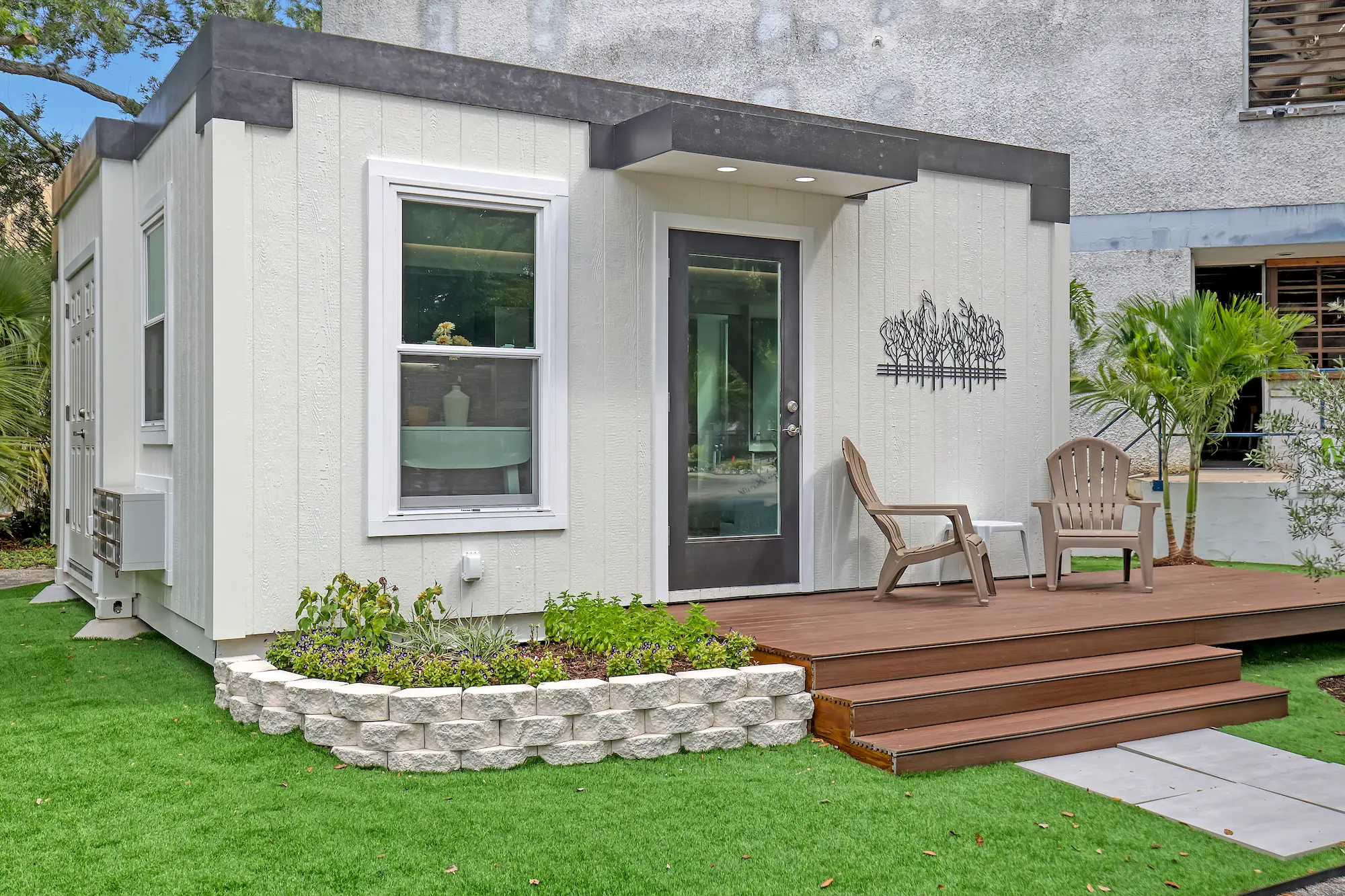 Exterior view of a compact modern ADU with flat roof and landscaped backyard with sun