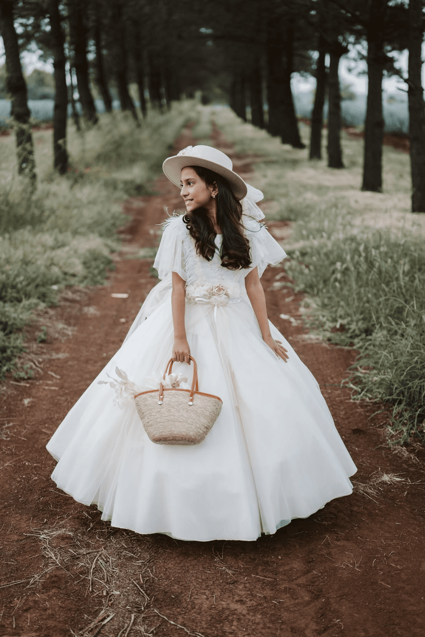 Modelo posando vestido blanco con bolsa de diseño en un campo