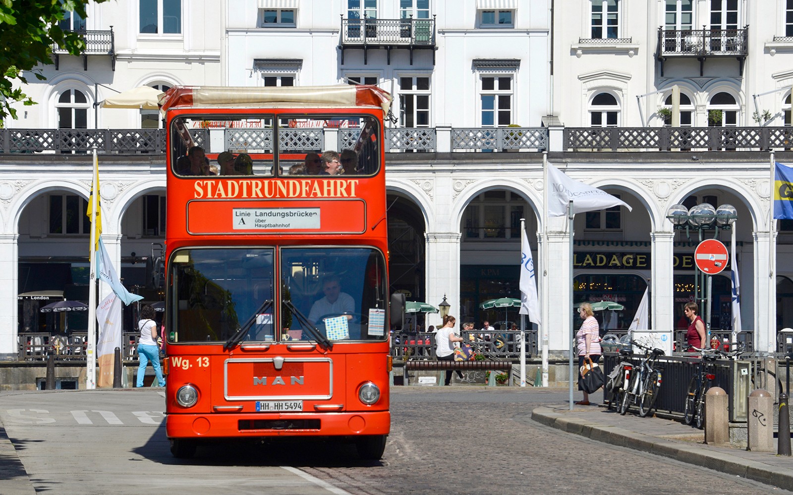 在历史悠久的白色建筑前,参加汉堡观光游的红色双层巴士。