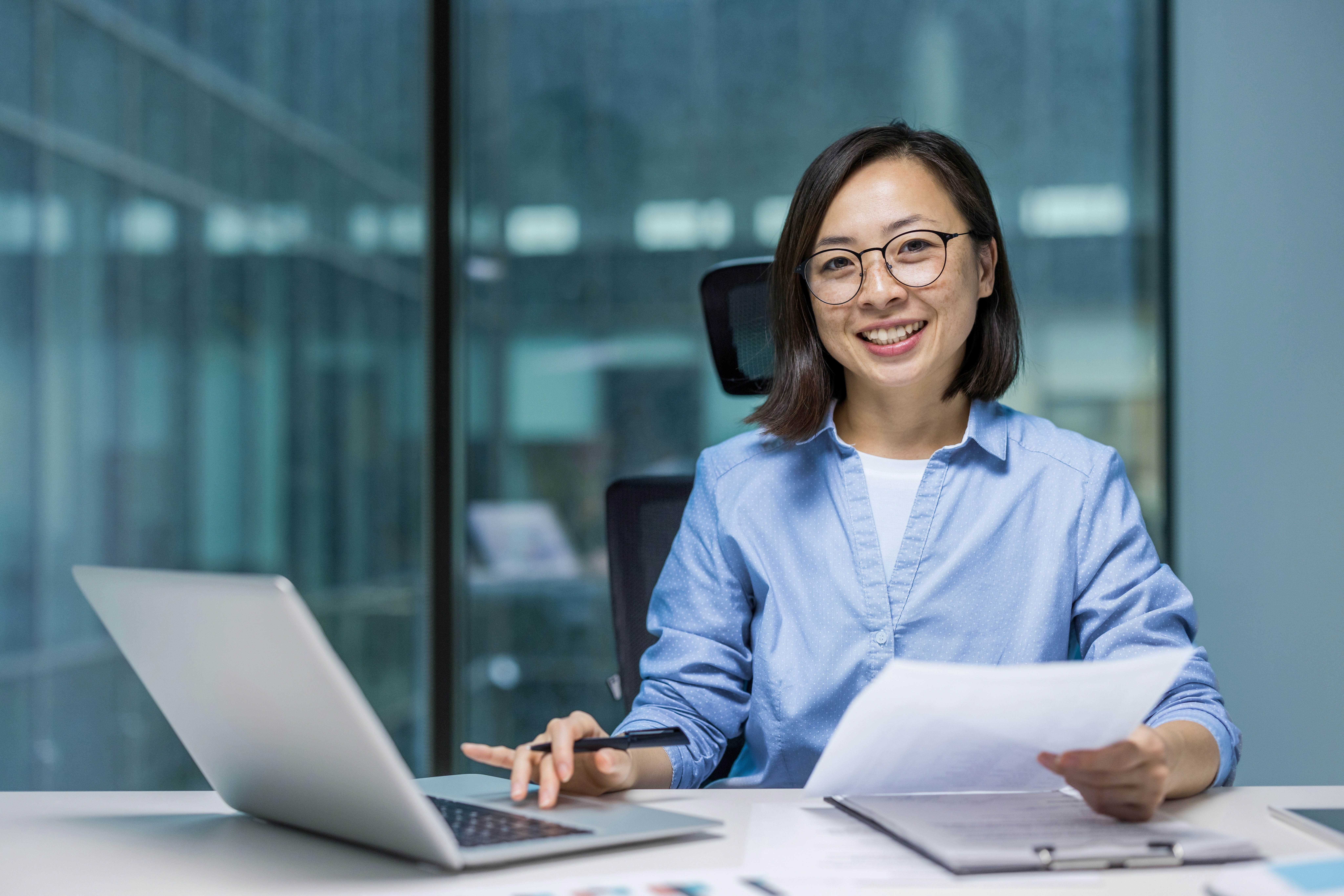 Young person with short, tousled blonde hair wearing an oversized, vibrant orange turtleneck sweater against a soft grey background, conveying a cool, modern look.