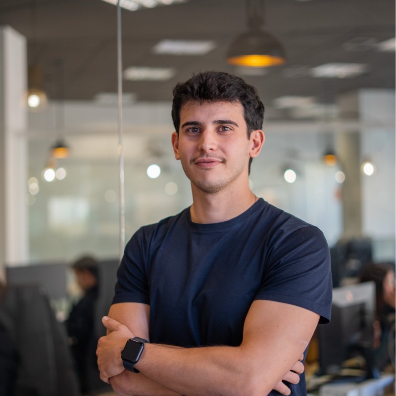 Giovane sorridente in ufficio, con uno smartwatch