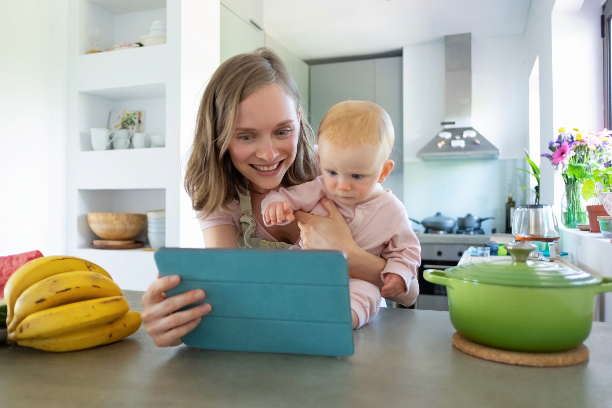 Mom holding baby while showing him a recipe on her ipad