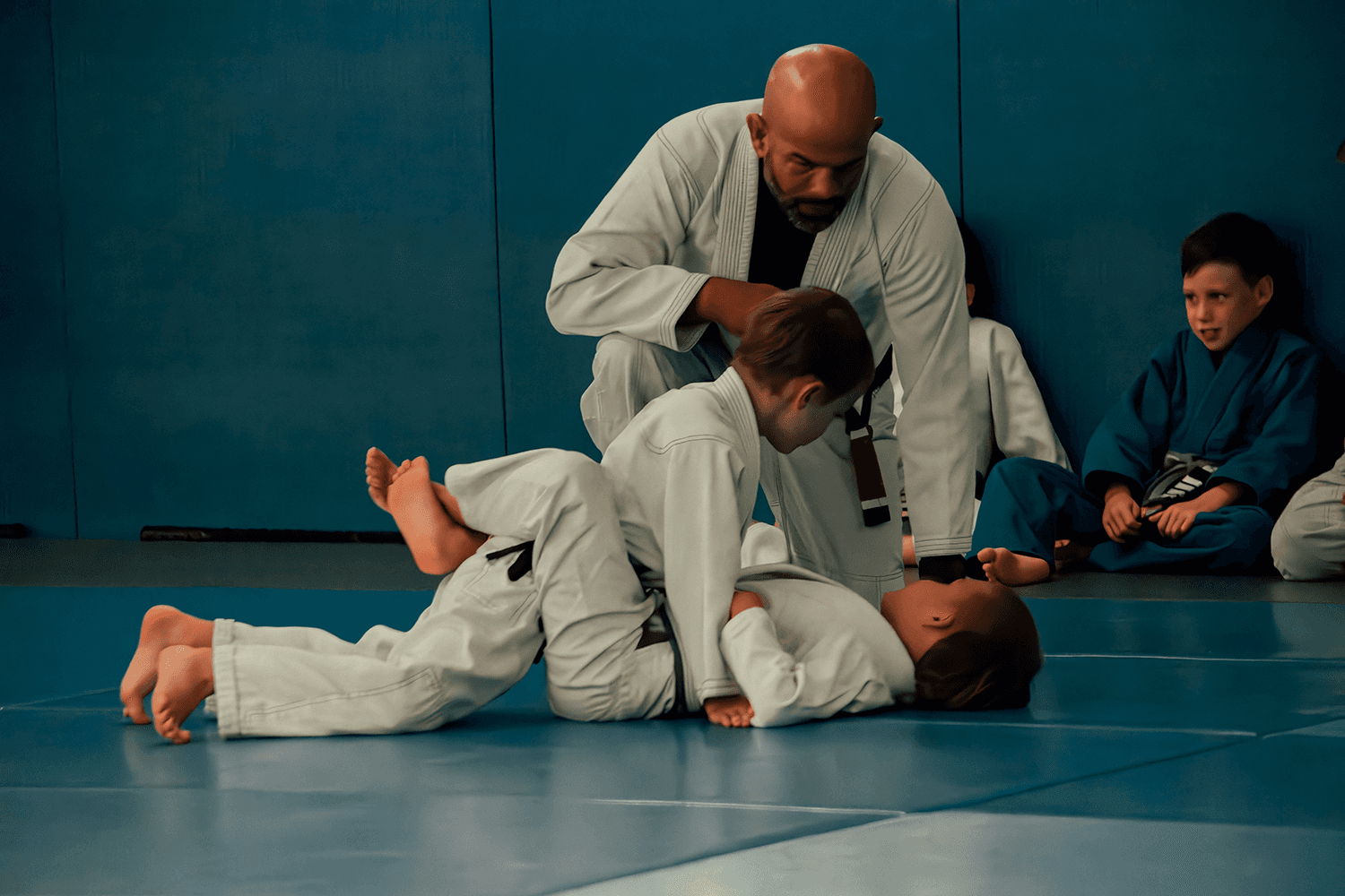 Instructor guiding a student through a ground technique on the mats