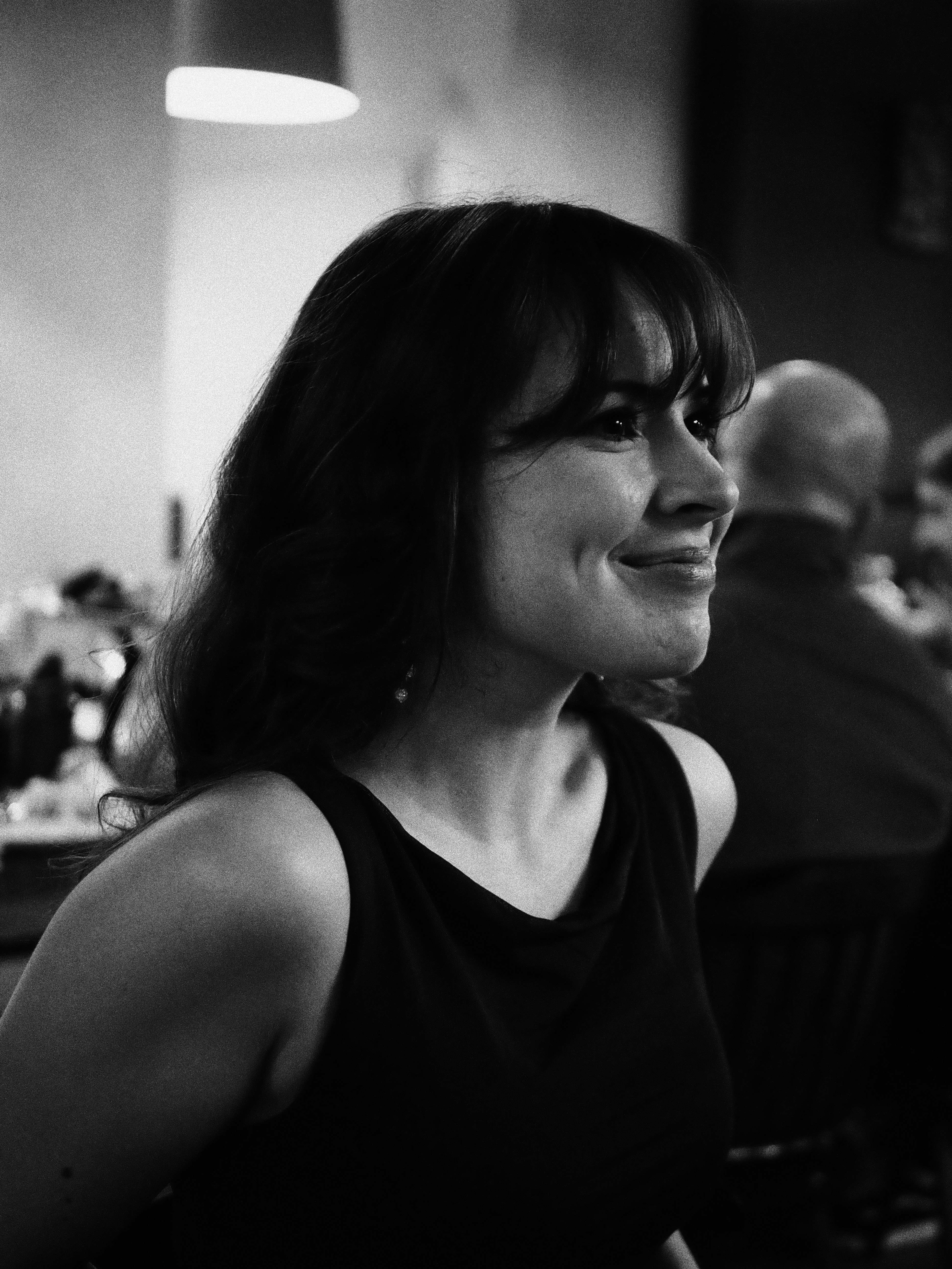 A thoughtful young person with dark hair gazes to the side, captured in soft black and white lighting.