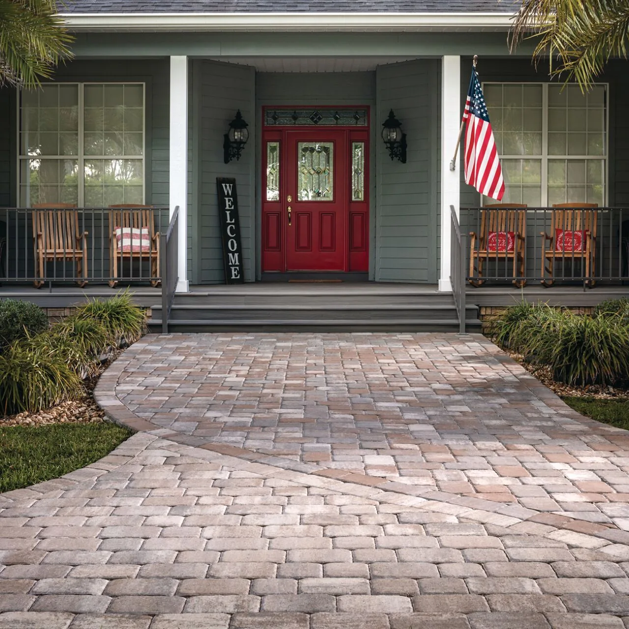 Curving paver walkway leading through a front garden to a red entrance door.