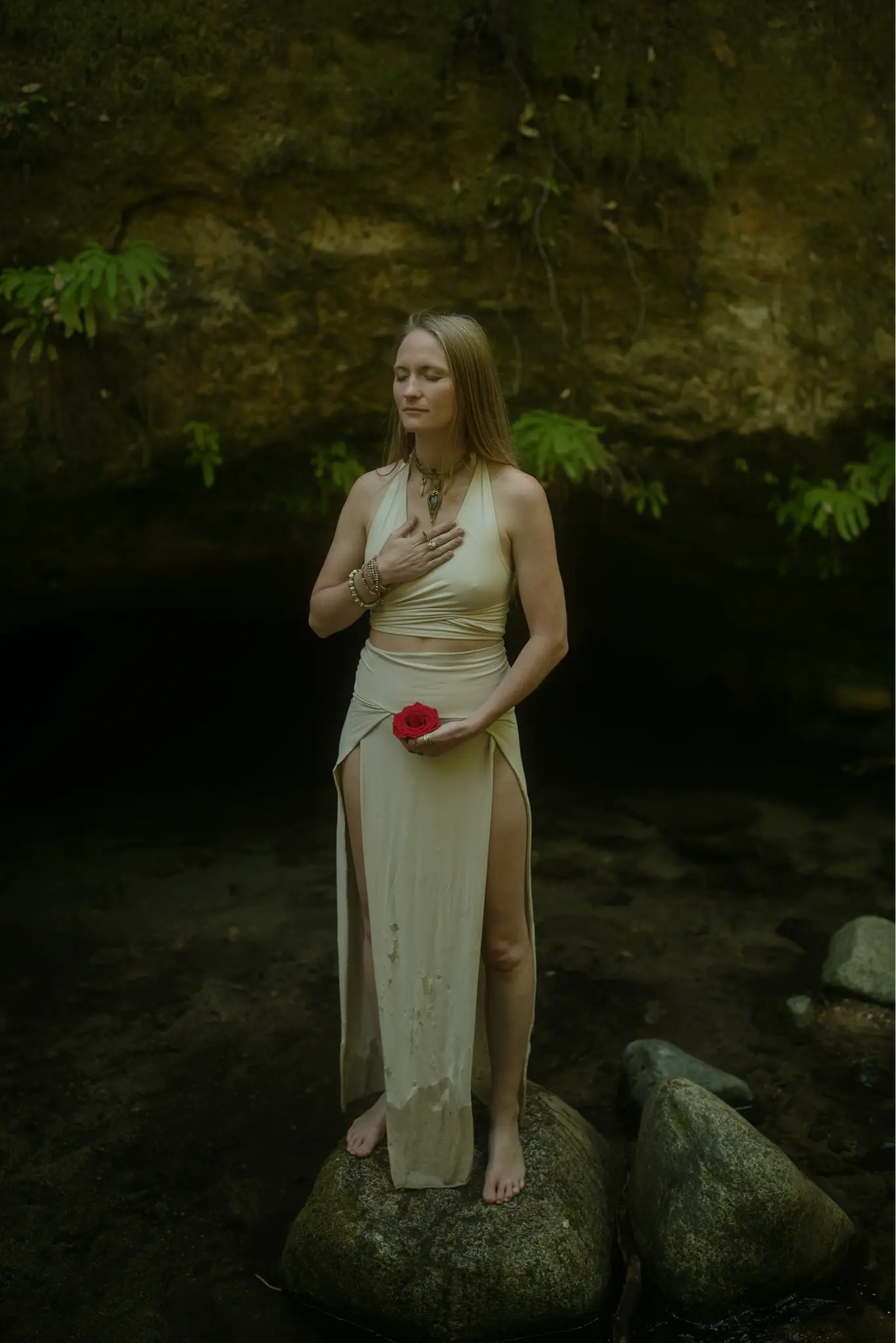 Emeline Crutcher, founder and shamanic guide of Tree of Life Temple, standing in jungle holding a rose