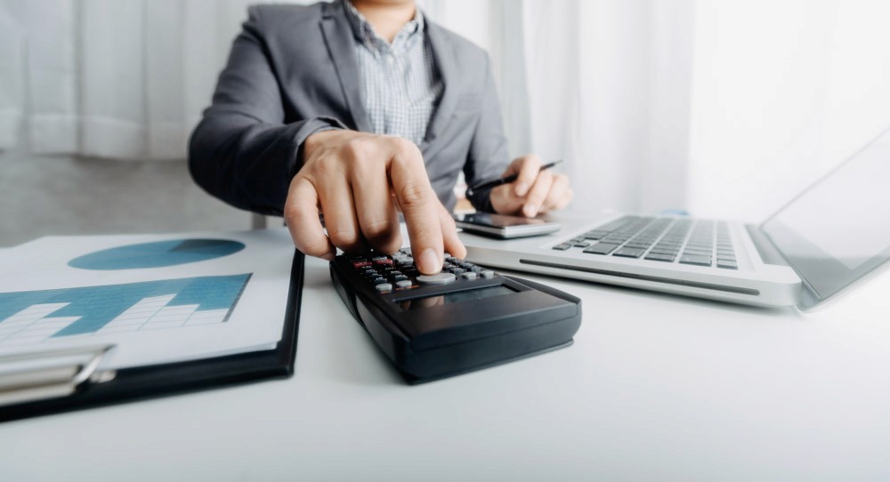 a group of people sitting around a table with laptops