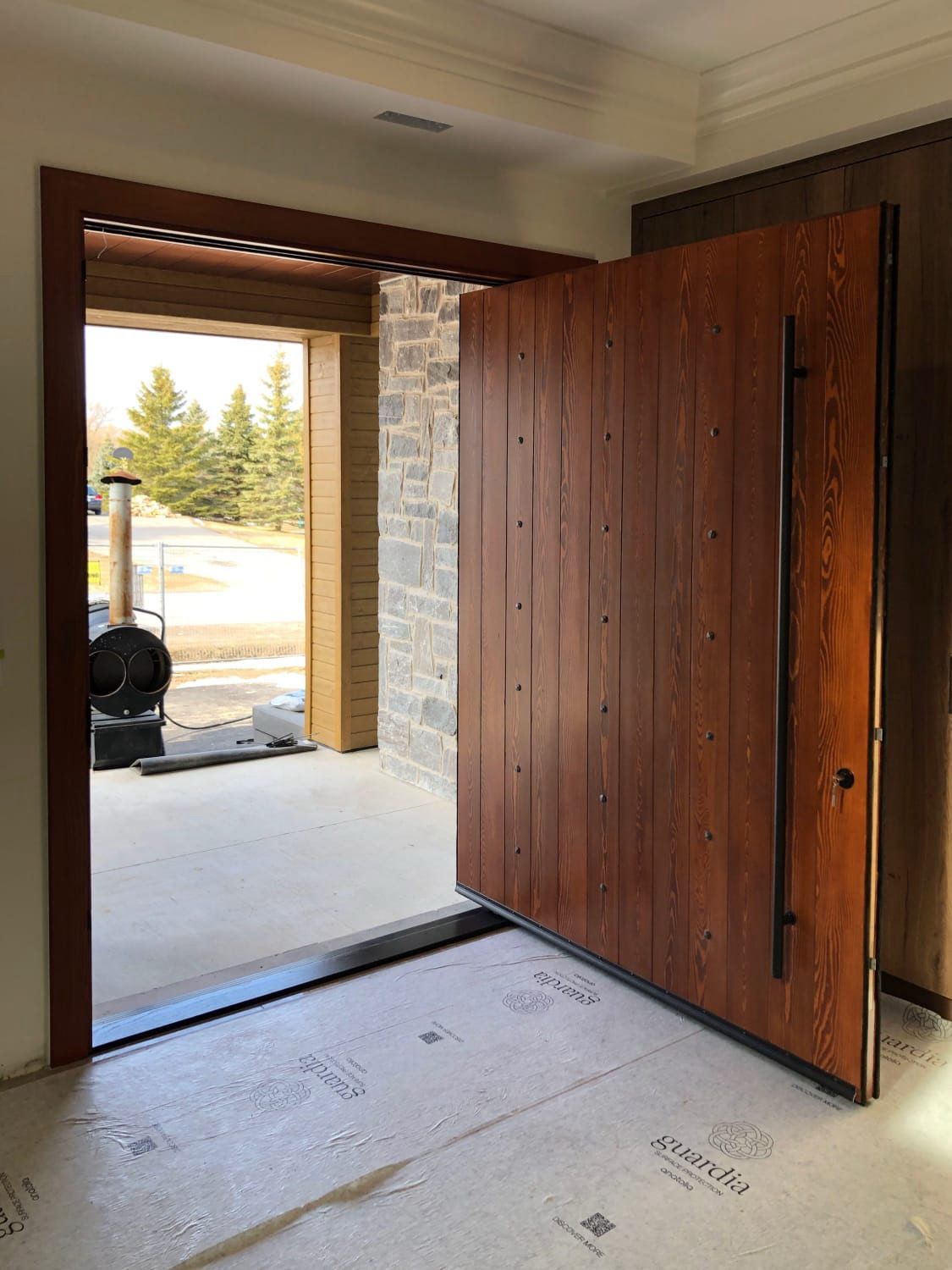 Grand custom entrance with a solid wood pivot door and floor-to-ceiling glass sidelights.