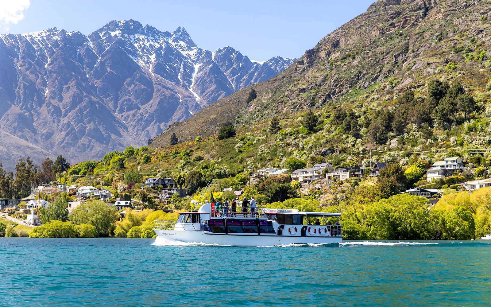 Brod za krstarenje na jezeru Wakatipu s putnicima koji promatraju planine Remarkables u Queenstownu.