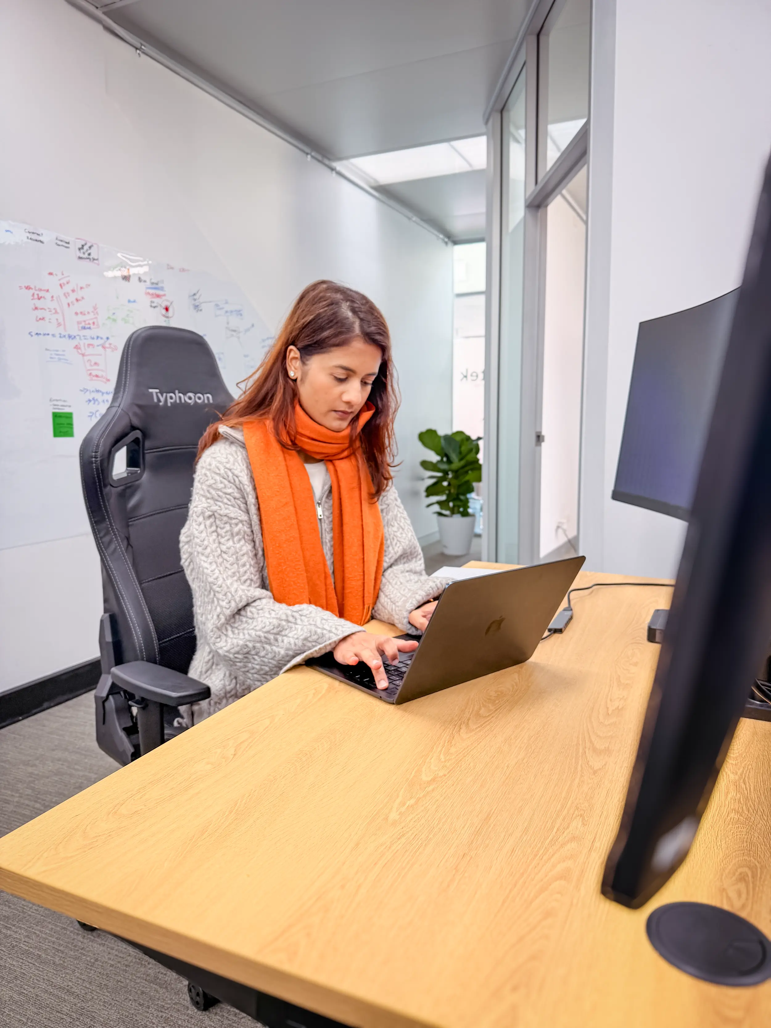 A recruitment professional focused at her desk, with analytics screens on the monitors in front of her.