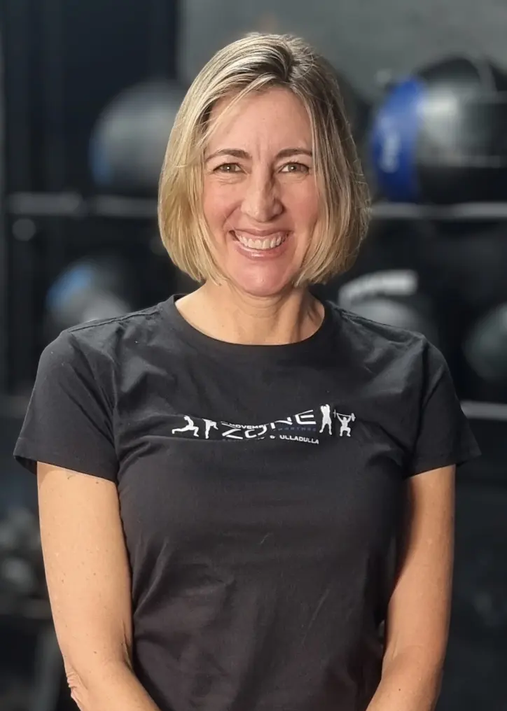 Coach Jon Rudd smiling in front of functional training equipment.