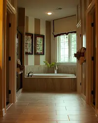 Warm wood-paneled bathroom with built-in bathtub, tiled floor, and large window