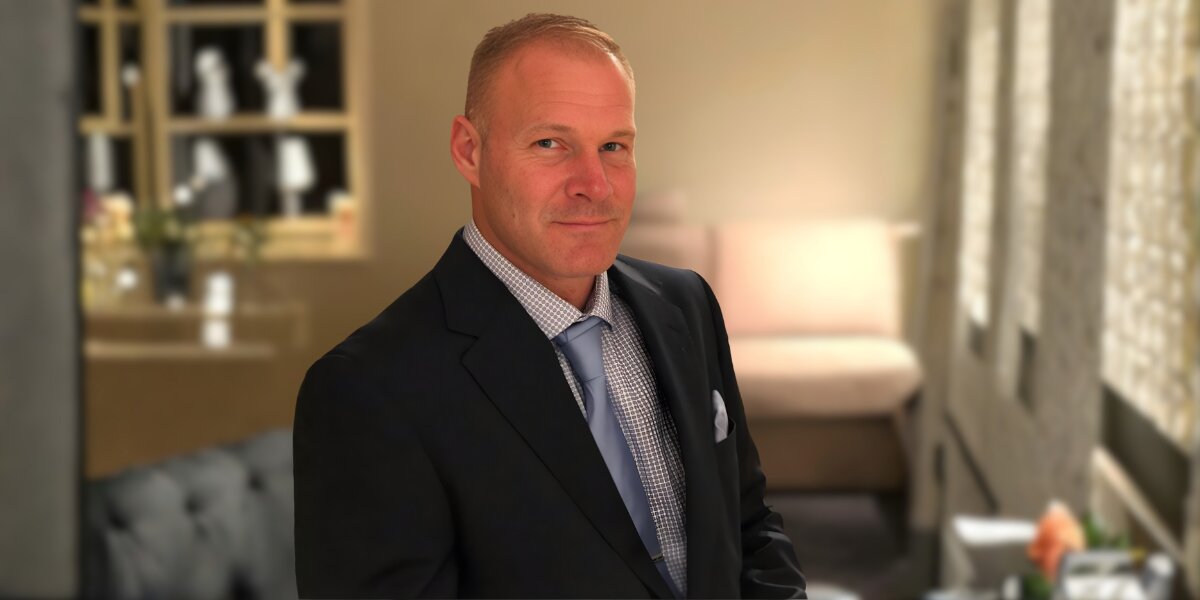 A man in a suit and tie stands in a room, embodying professionalism and purpose in a transformative environment.