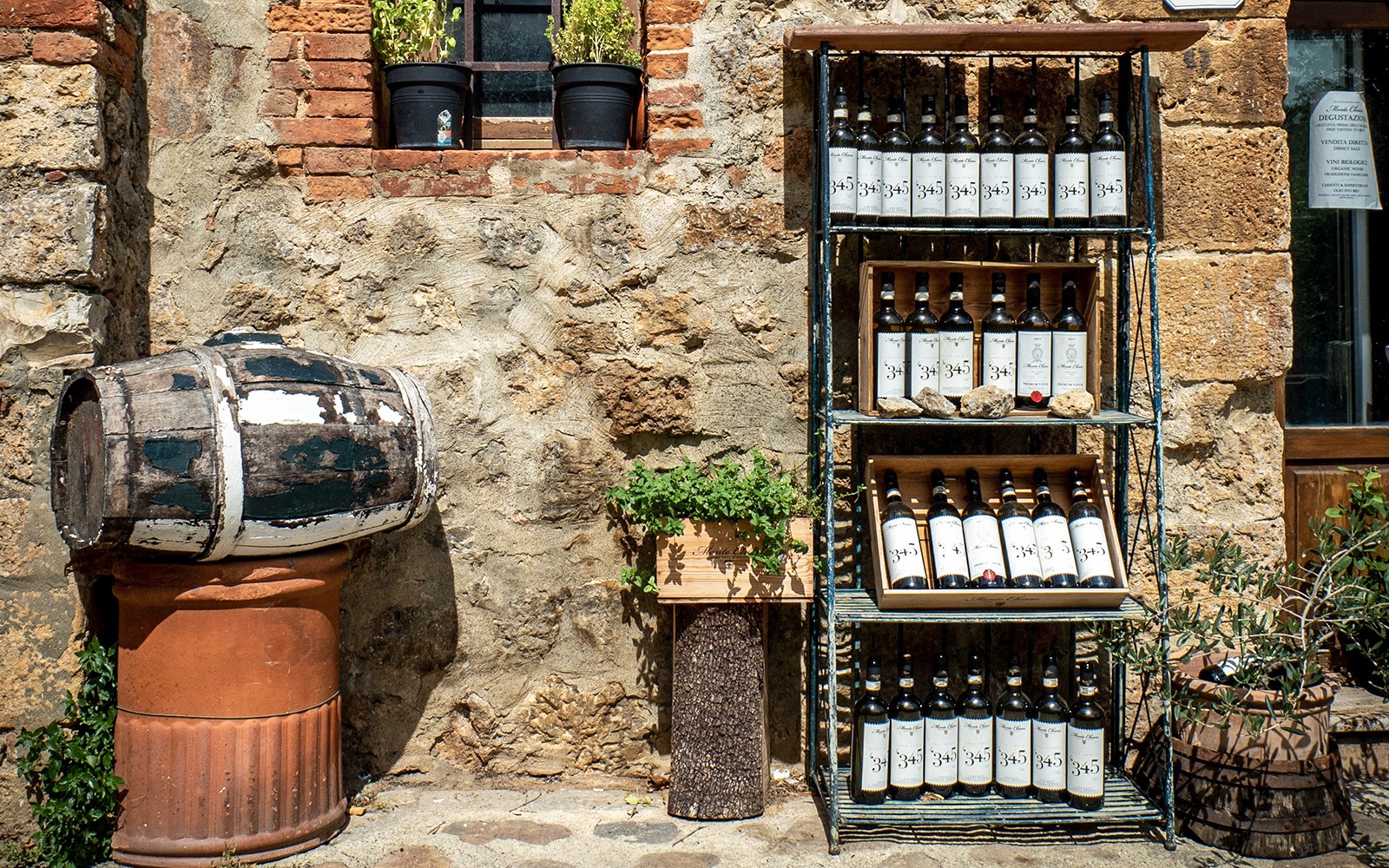 在电动自行车之旅中,酒瓶整齐地摆放在架子上,基安蒂庭院中还有一个质朴的酒桶。