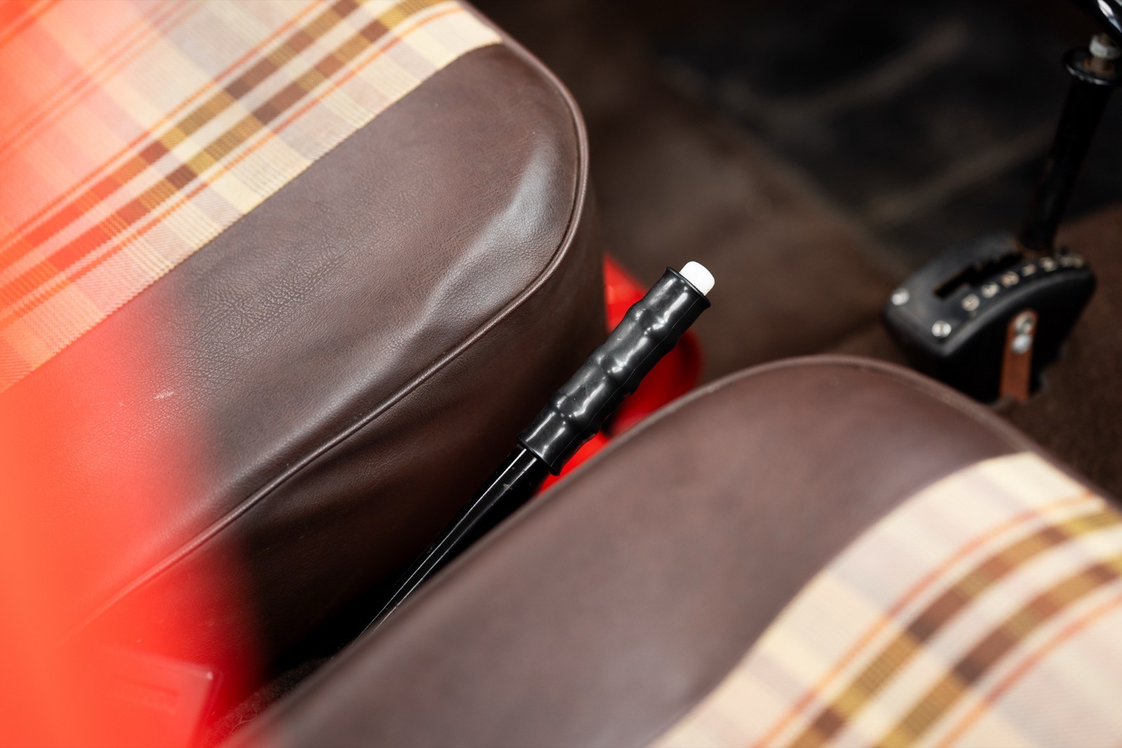 A close-up of car seats with a pen resting in the gap between them, highlighted by a red cloth.