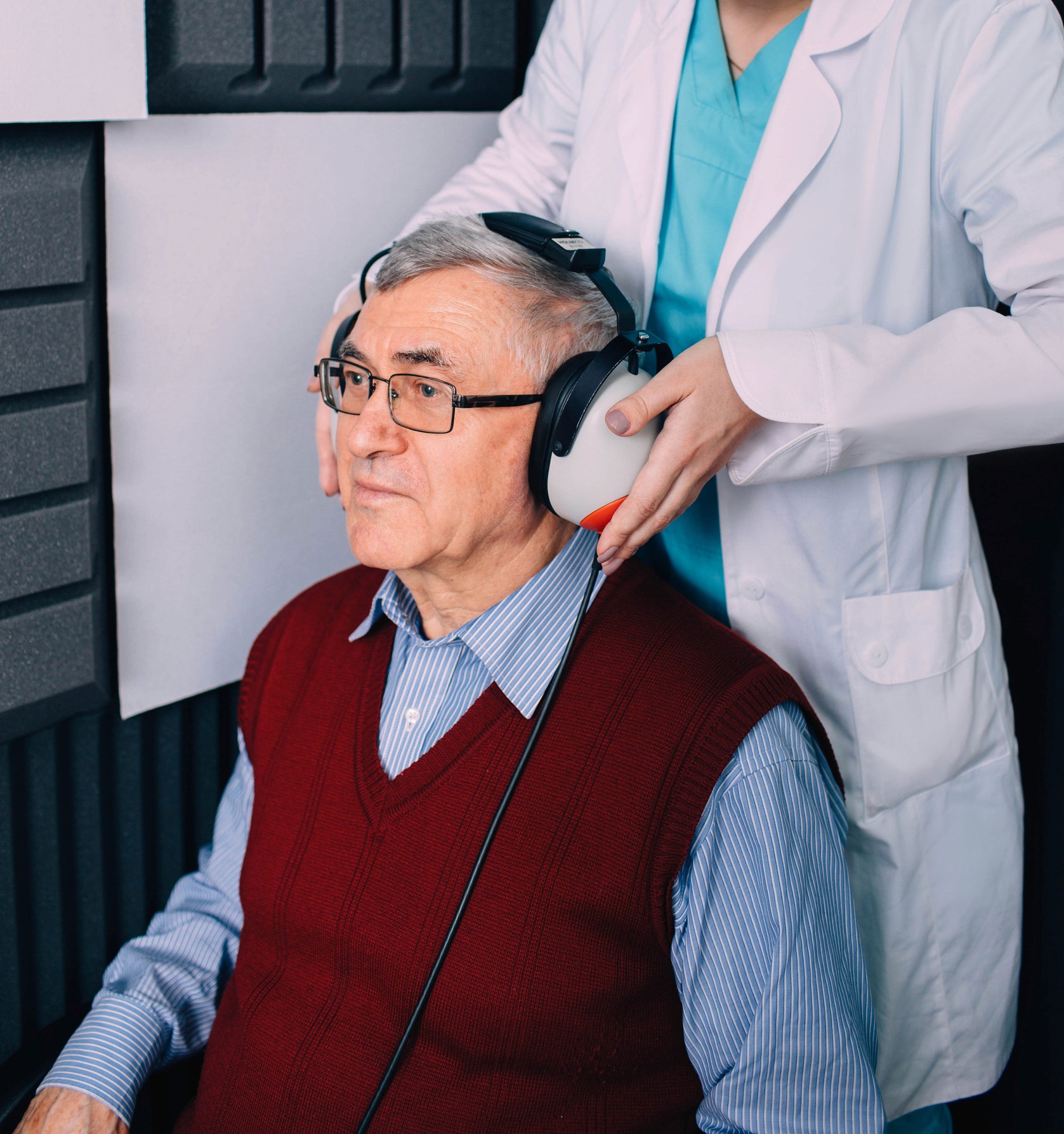 Hombre mayor recibiendo prueba auditiva con auriculares grandes durante el proceso de adaptación de audífonos