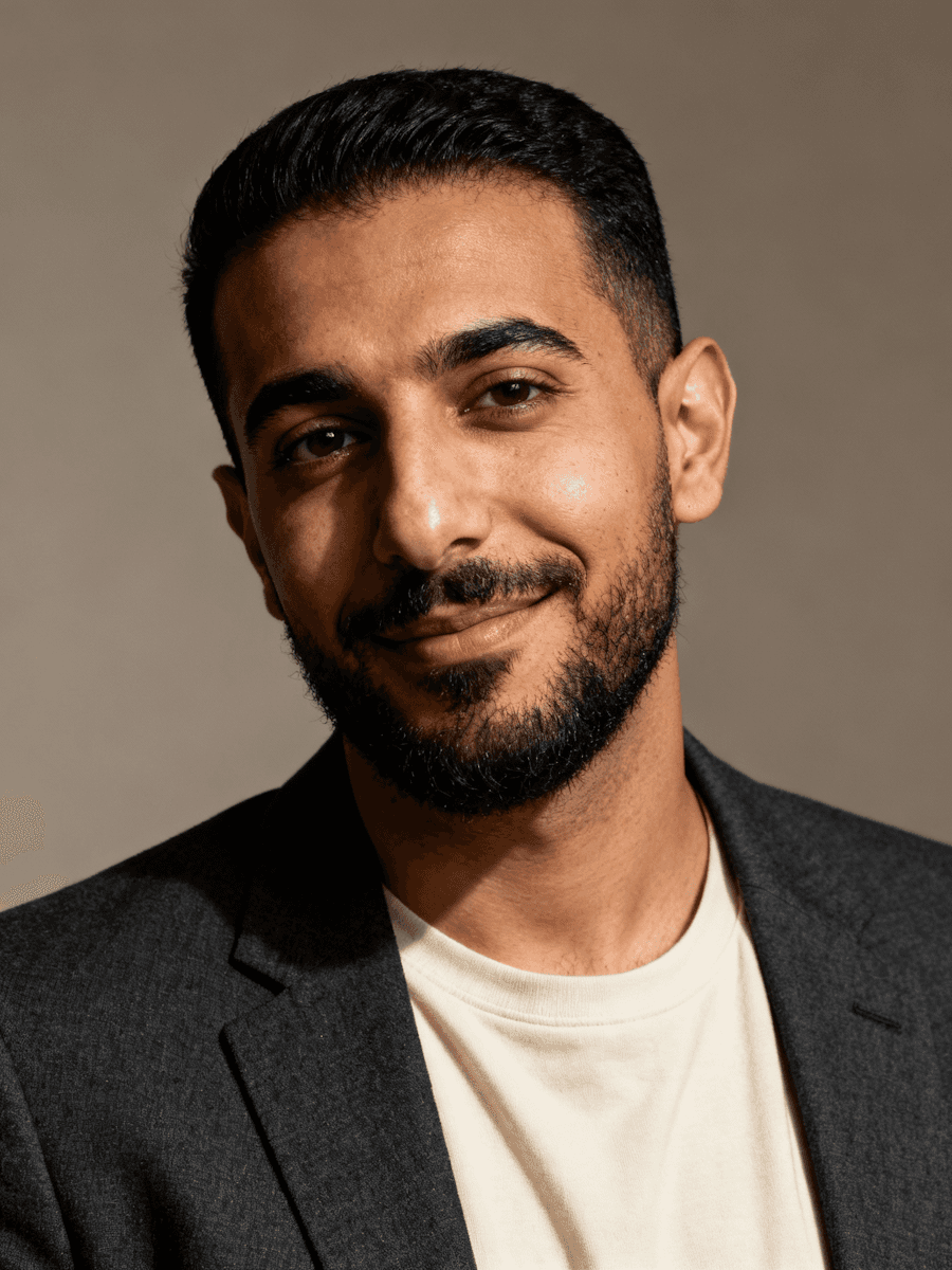 Portrait of woman with curly hair wearing navy blue cardigan over matching top, casual contemporary style on light background