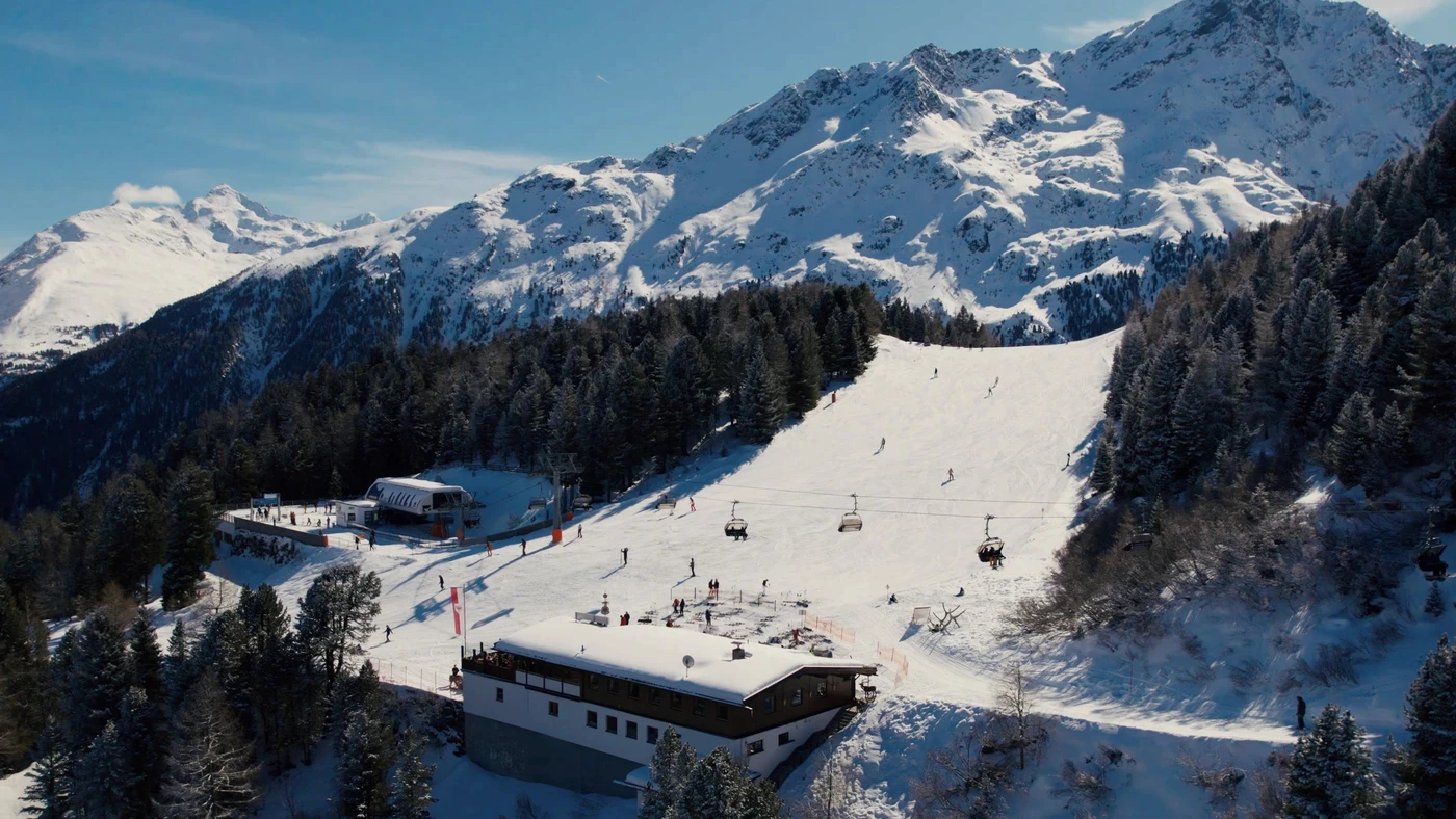 Eine Drohnenaufnahme der Bubis Schihütte an einem sonnigen Skitag.