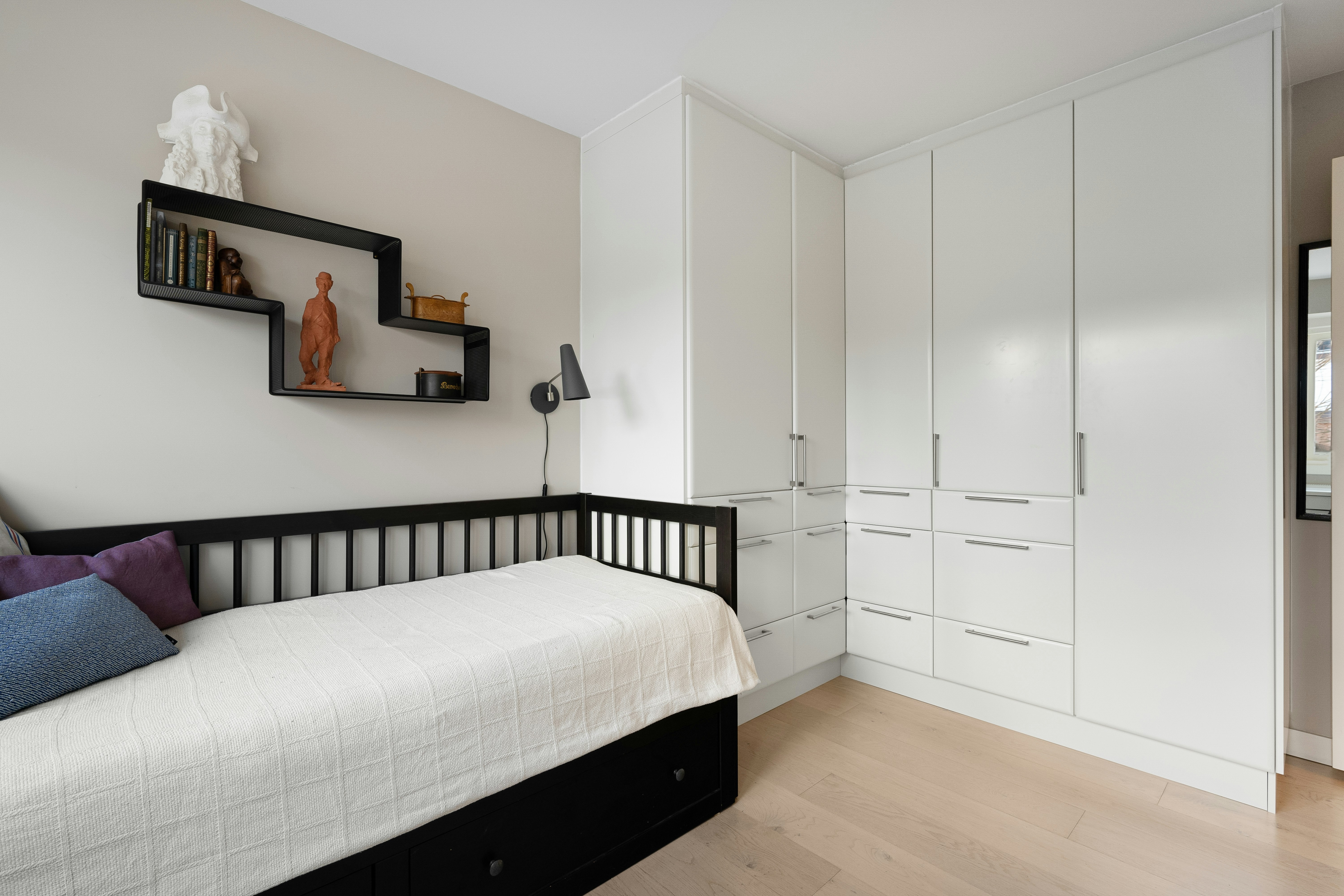 A bedroom with a bed, dresser, and mirror