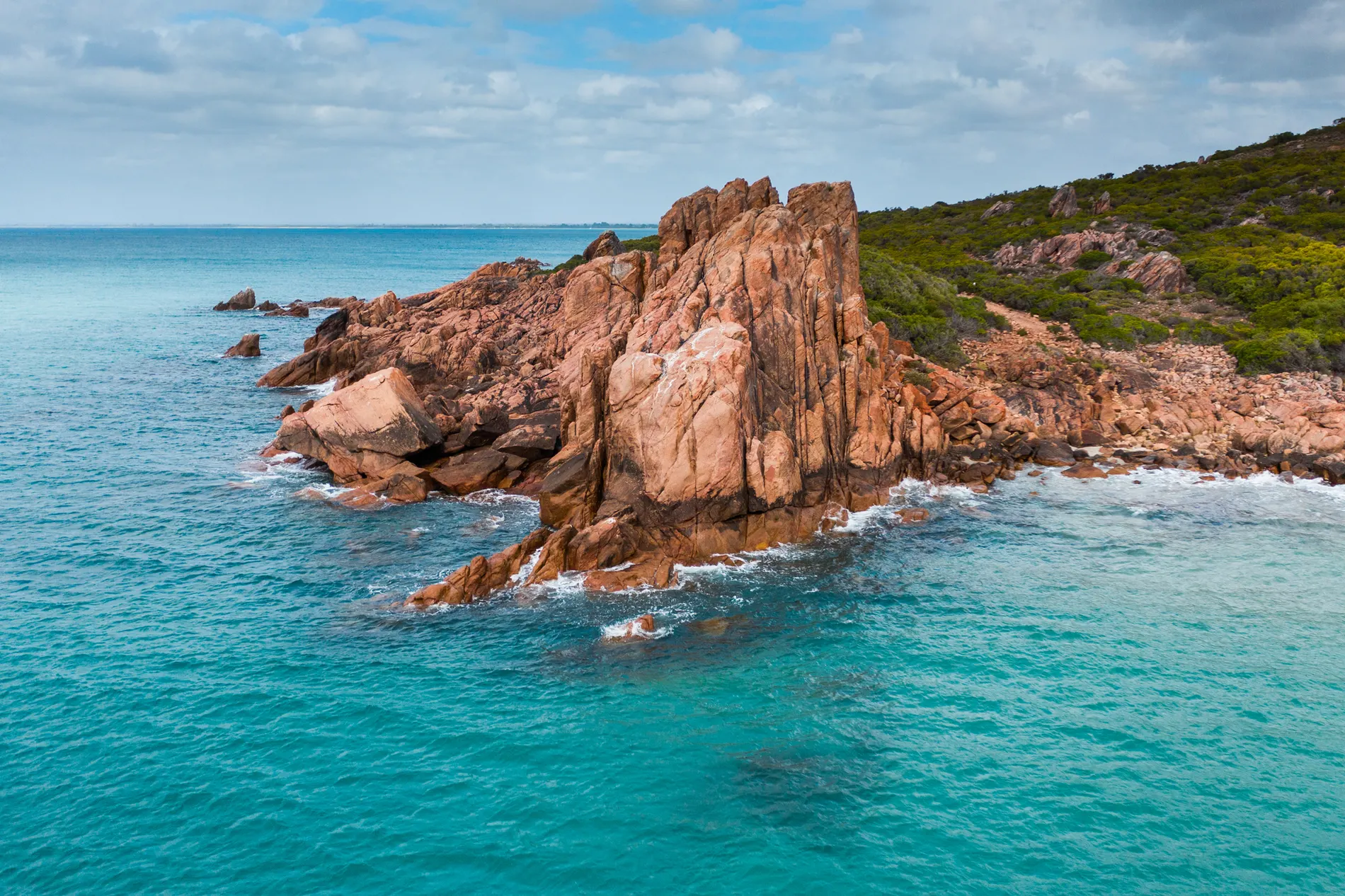A weathered granite headland standing above clear blue water