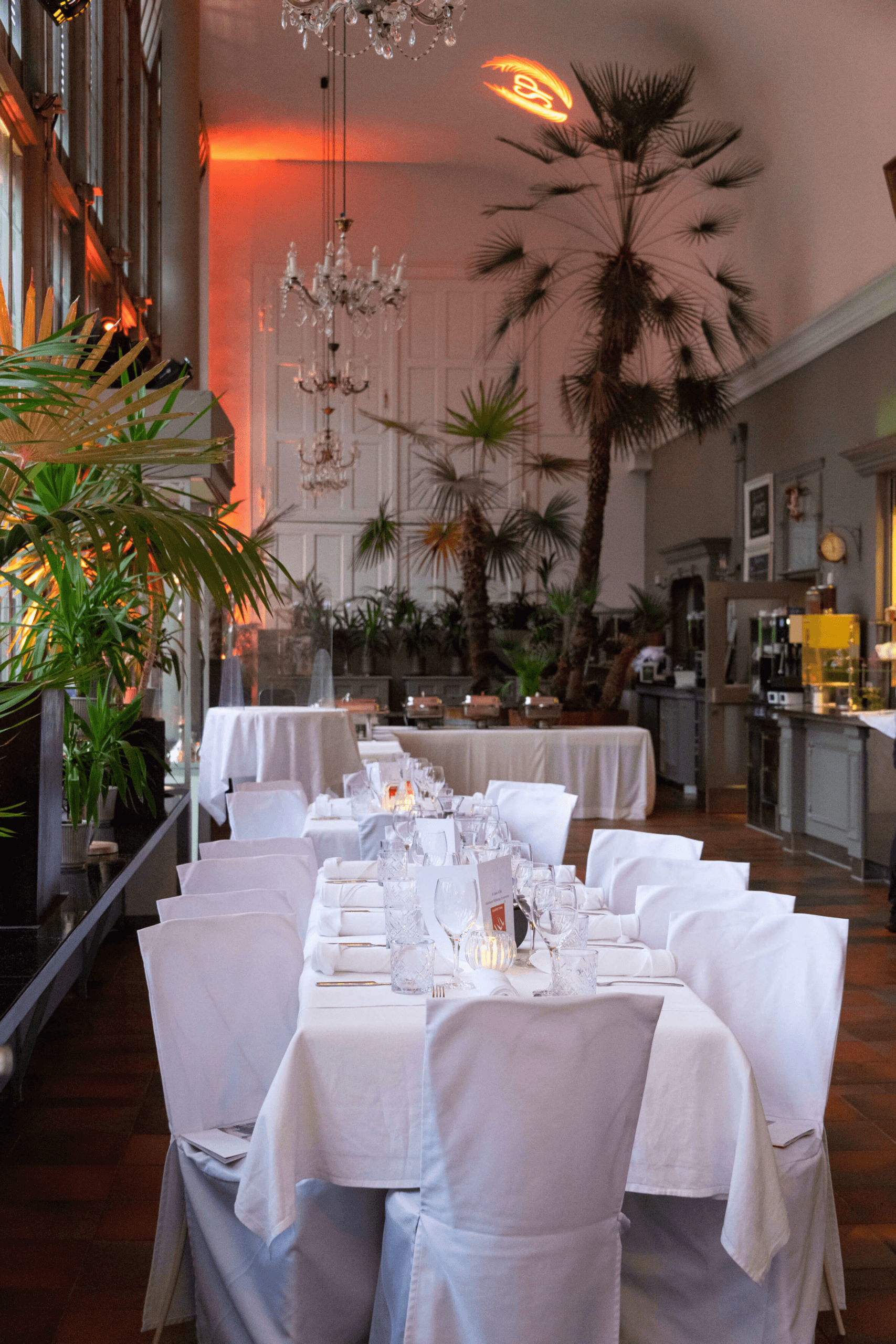 An elegant wedding ceremony setup features a domed gazebo adorned with peach and pink floral arrangements and lush greenery. White chairs line the aisle.