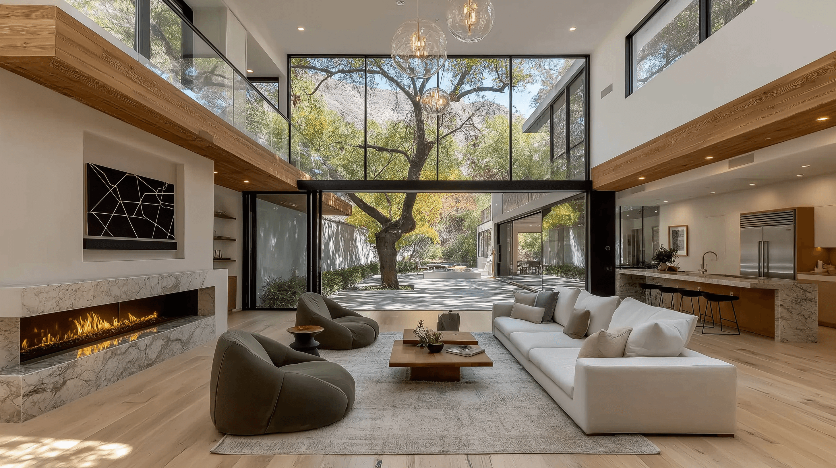 Open-concept modern living room with a long marble fireplace, green lounge chairs, and a massive glass wall that completely retracts to reveal an outdoor courtyard with a large mature tree.