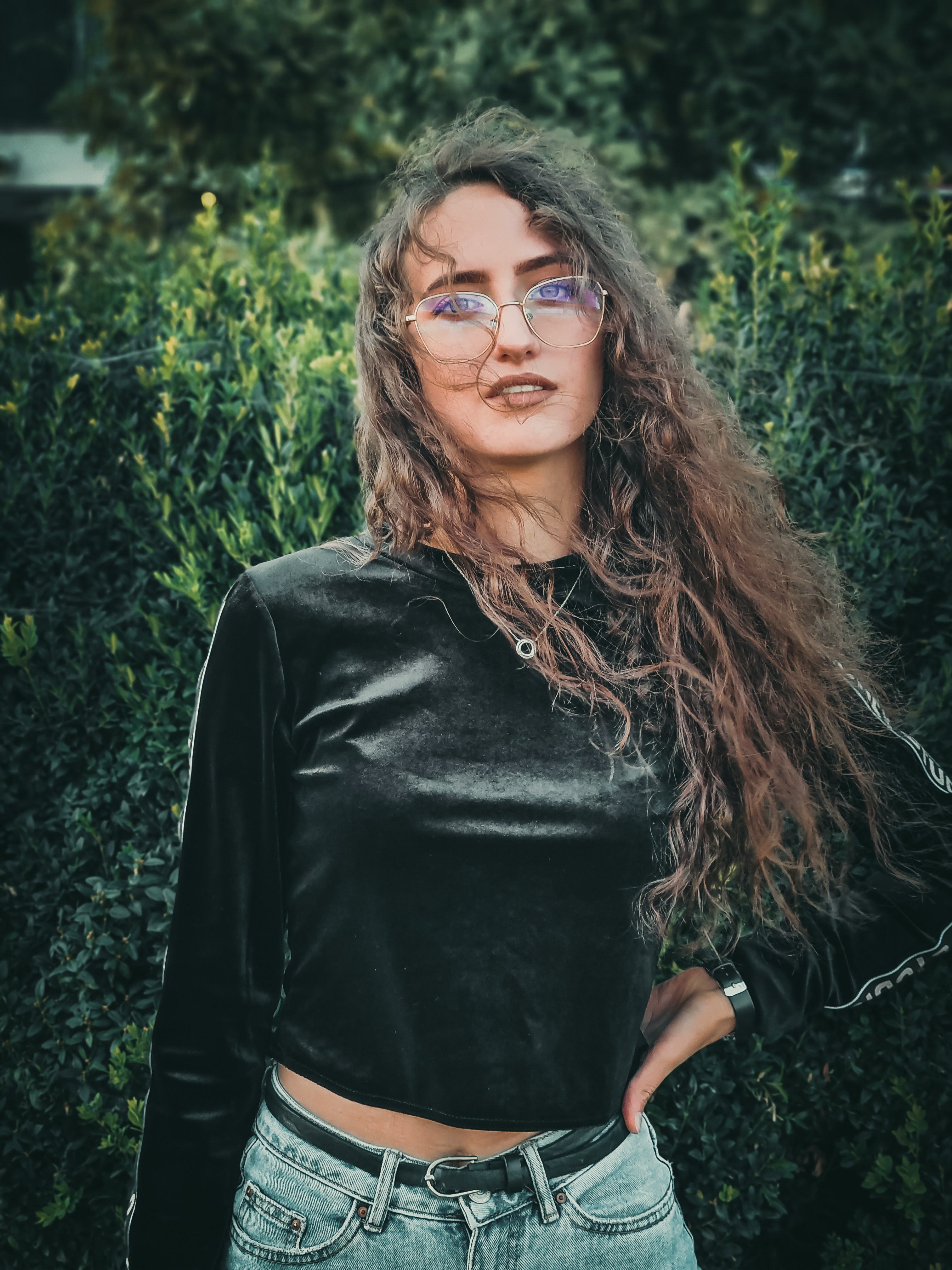 woman in black long sleeve shirt wearing black framed eyeglasses standing near green plants during daytime