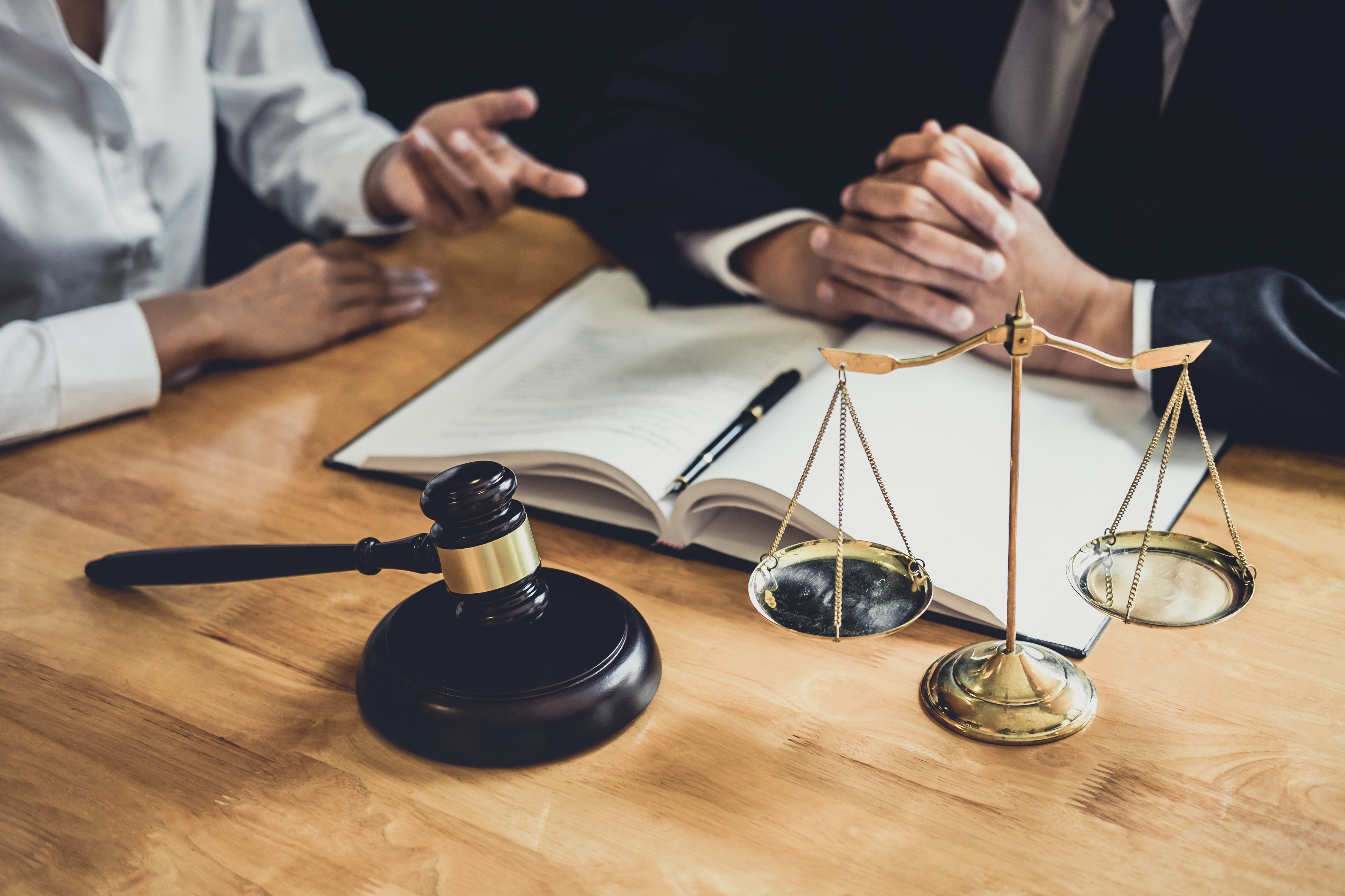 Judge's gavel and scales of justice on a desk with two people reviewing legal documents, representing the impact of bankruptcy on alimony and child support obligations in Massachusetts