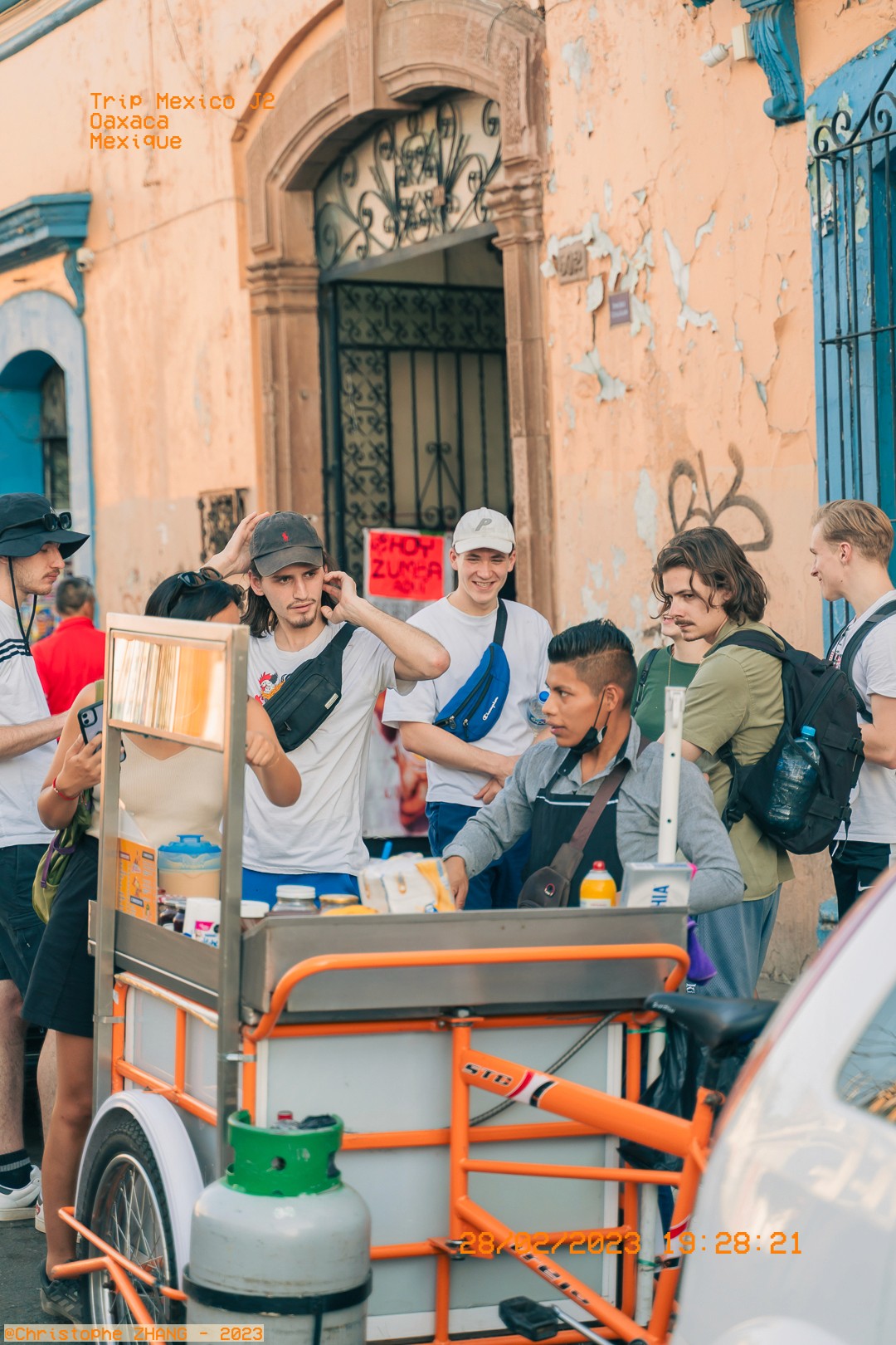 Scène de rue à Oaxaca avec des jeunes autour d'un stand de nourriture mobile.