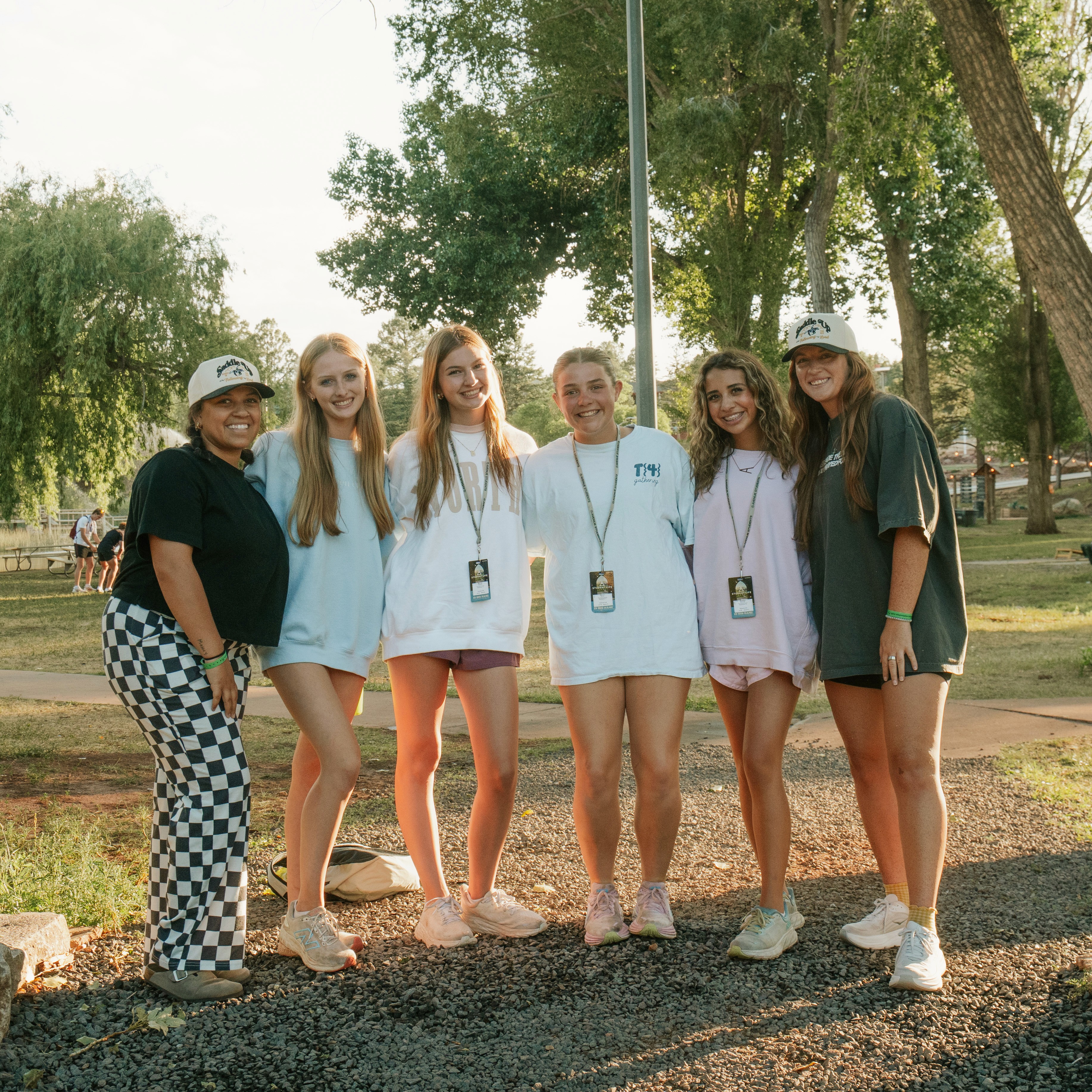 Two boys smiling outdoors, one in a yellow shirt and sunglasses, posing with peace signs. Green trees in the background.