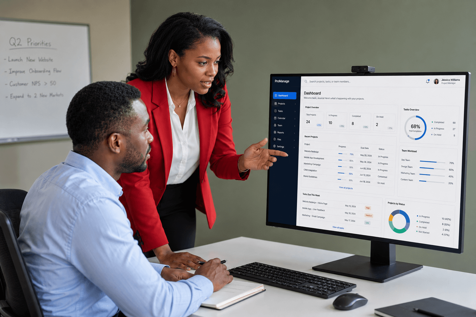 Two professionals collaborate at a desk, discussing a project displayed on a computer screen in a modern office setting.