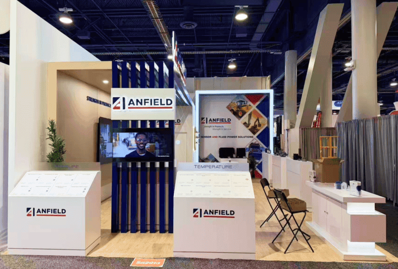 ANFIELD CONEXPO 2026 20x30 booth with product display counter, construction equipment graphics, and visitor discussion area