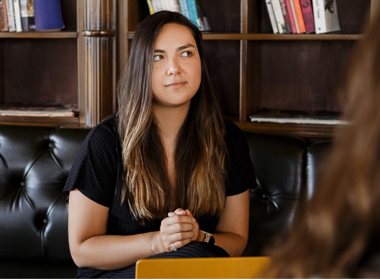 Elisabeth Mayr sitting in a coffeeshop, taking a pause to think while Talking to a friend