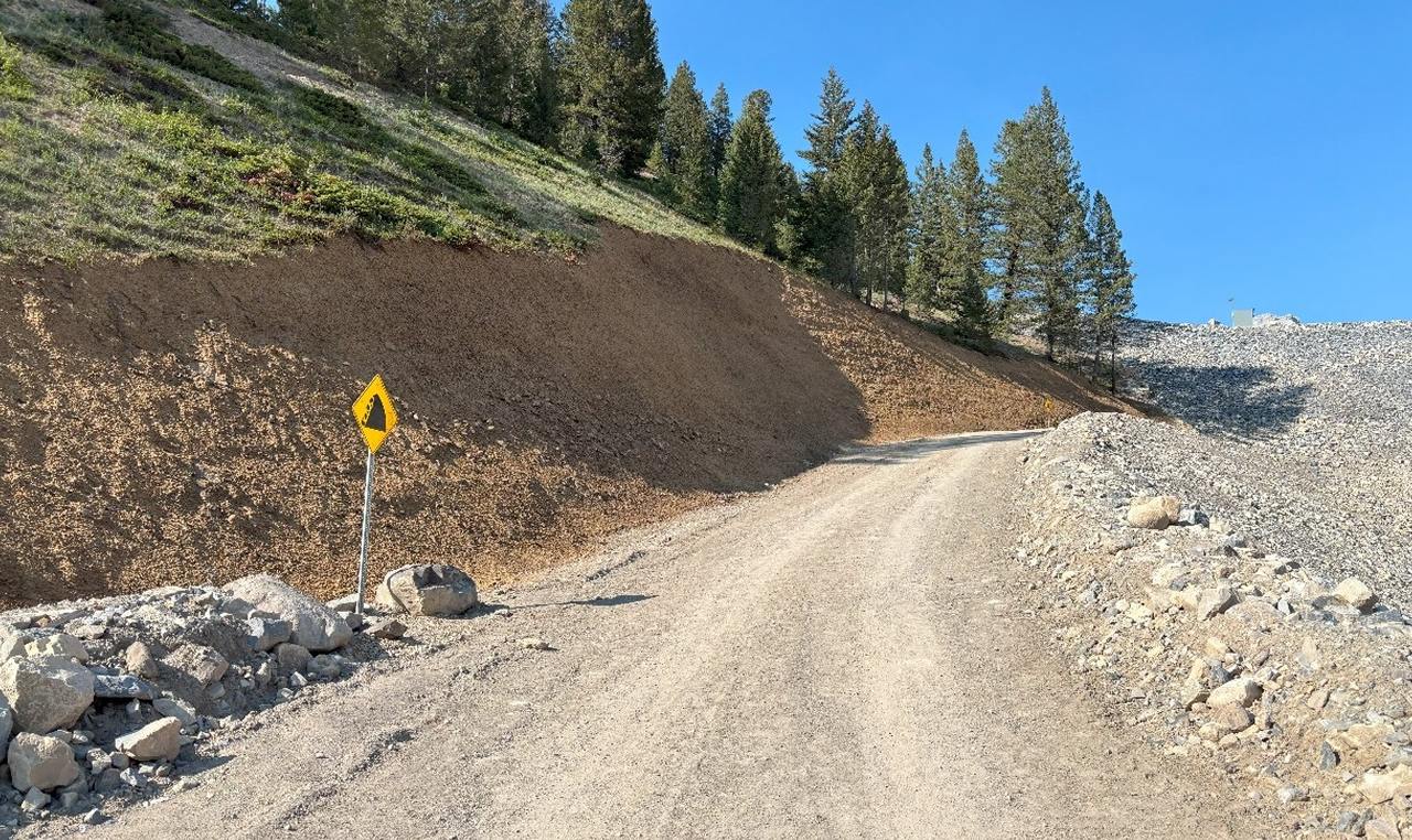 Completed steep-grade construction access road with safety berms leading to Cougar Creek Dam