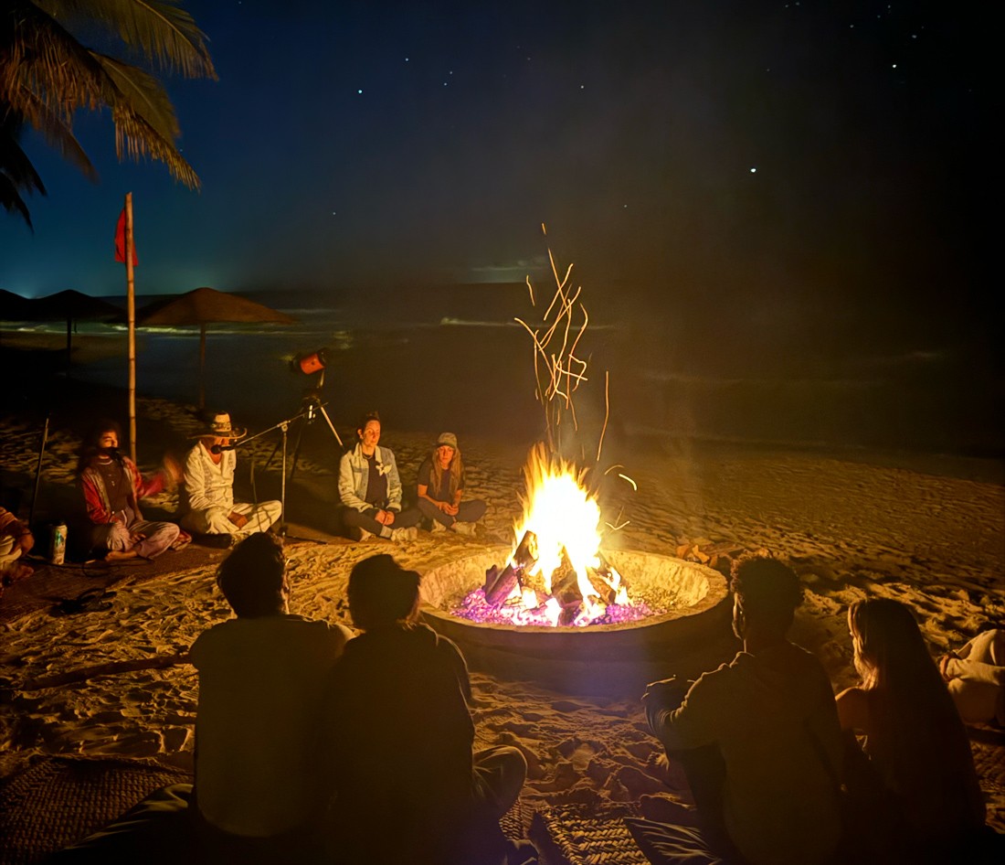 People creating a mandala with hands under a tent at Nômade Tulum, Mexico.