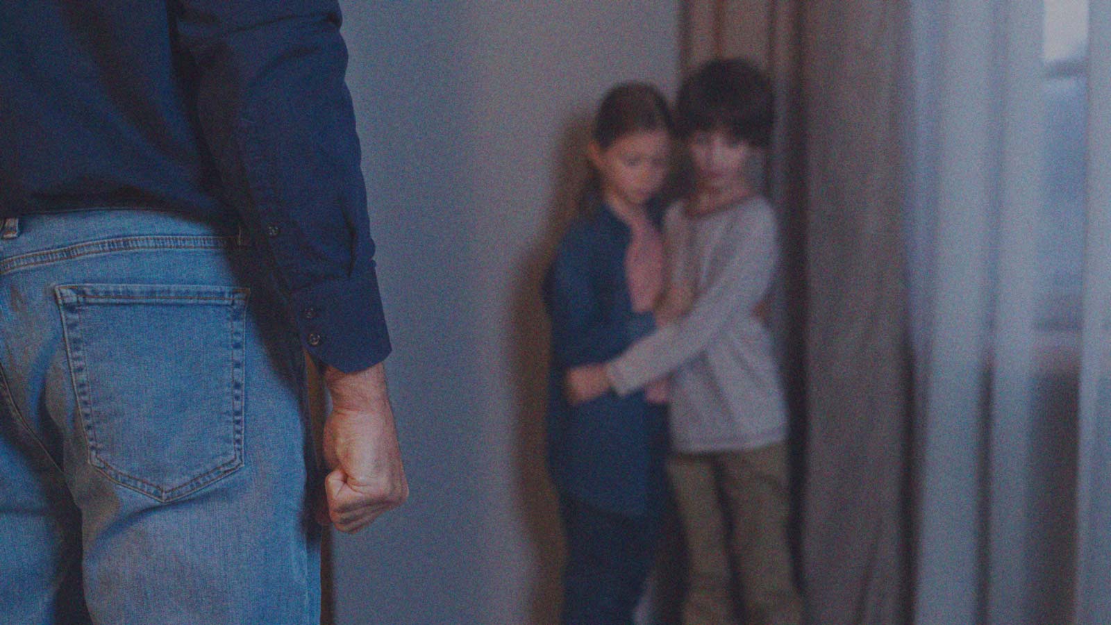 Foto de la silueta de un hombre frente a dos niños asustados, en la columna de opinión Cuando el crimen organizado toca la puerta de la niñez de IdeaPaís.