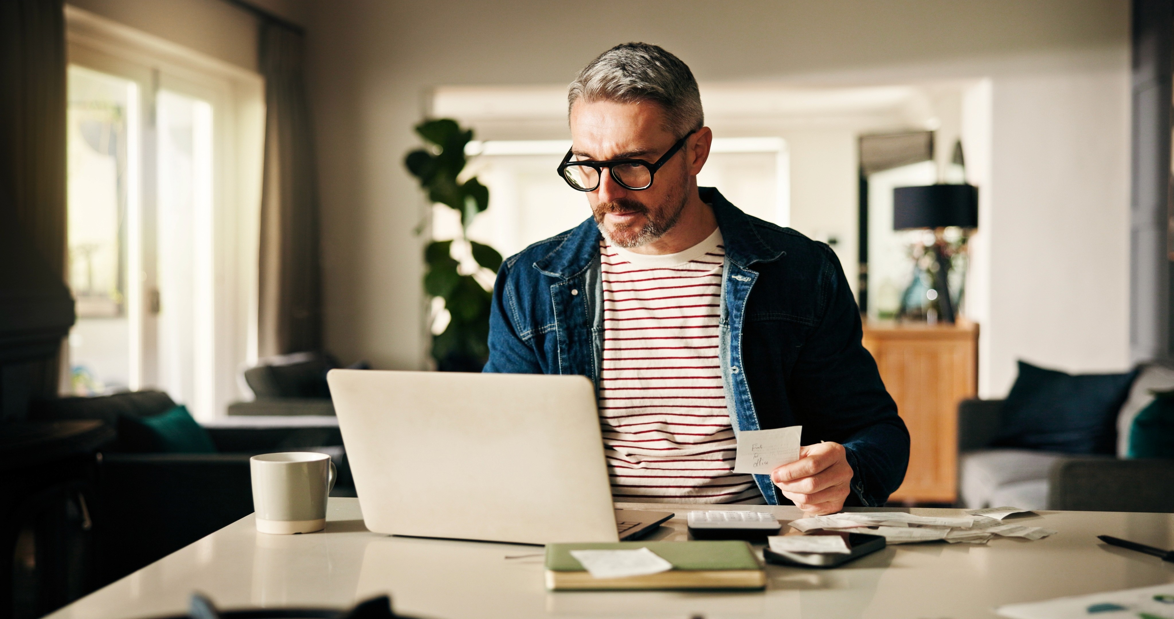 Close-up of hands typing on a laptop keyboard on a wooden desk, with the screen turned off.
